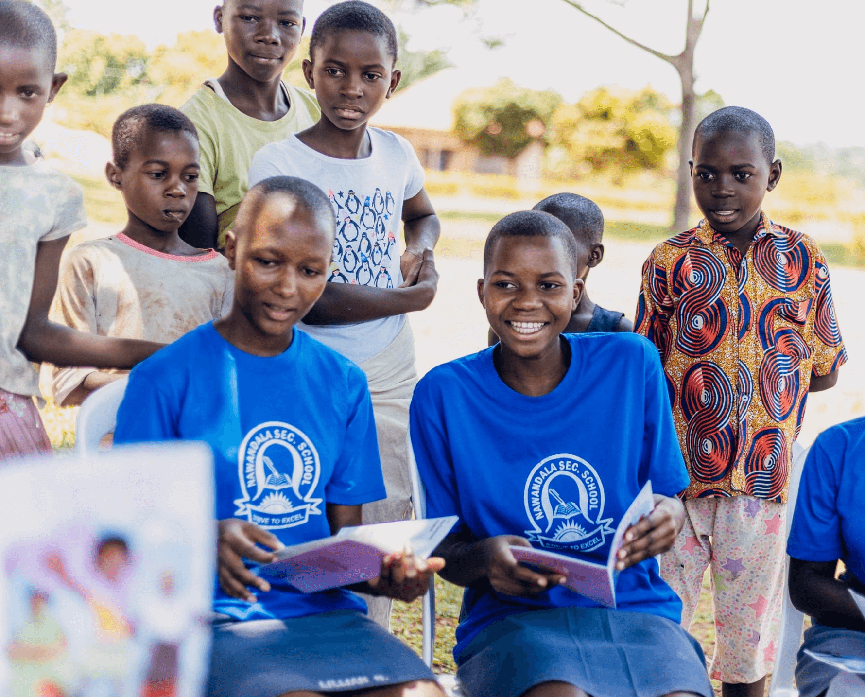 Girls smiling while holding an educational book created by She For She