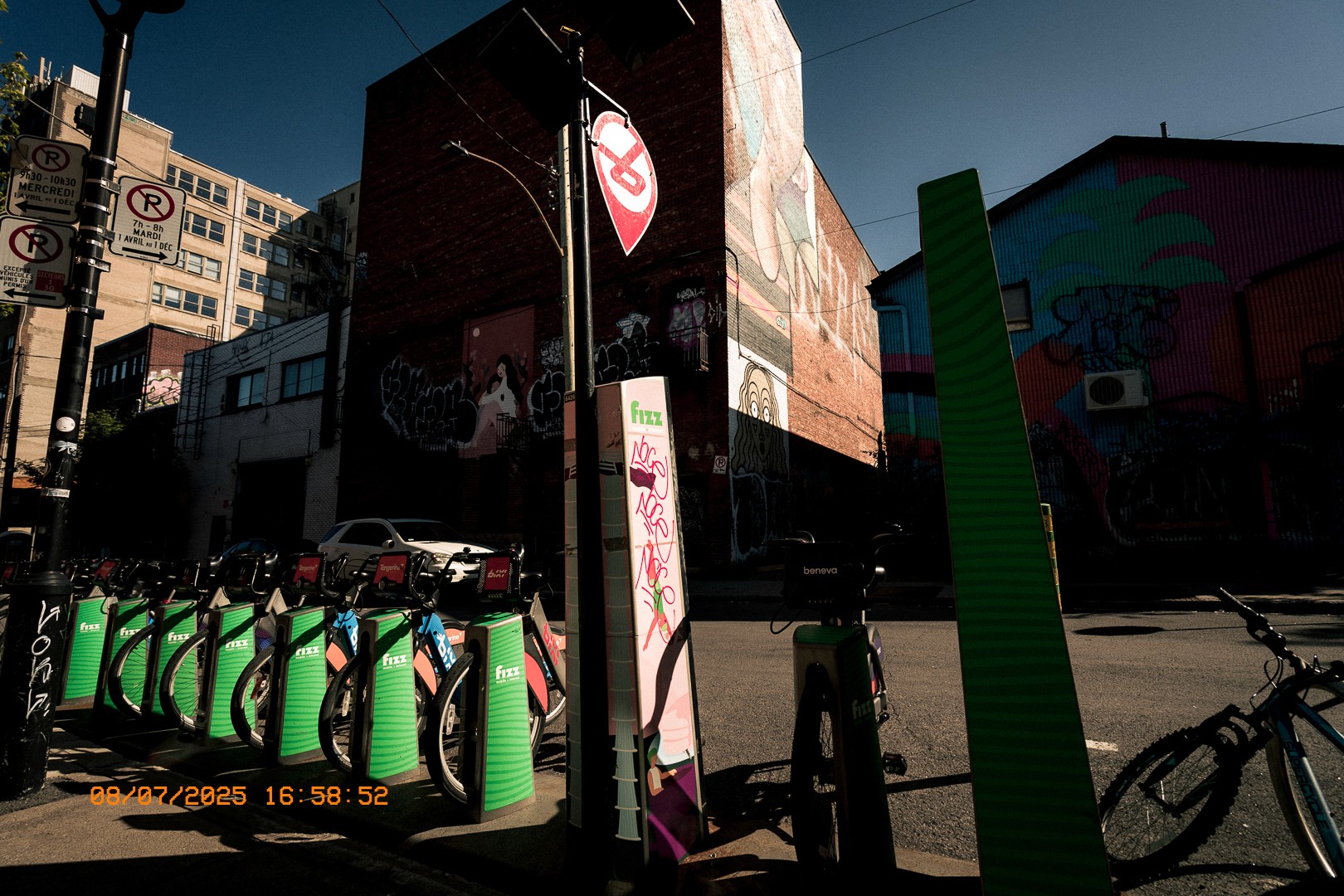 Rangée de vélos en libre-service Bixi devant des fresques murales colorées à Montréal.