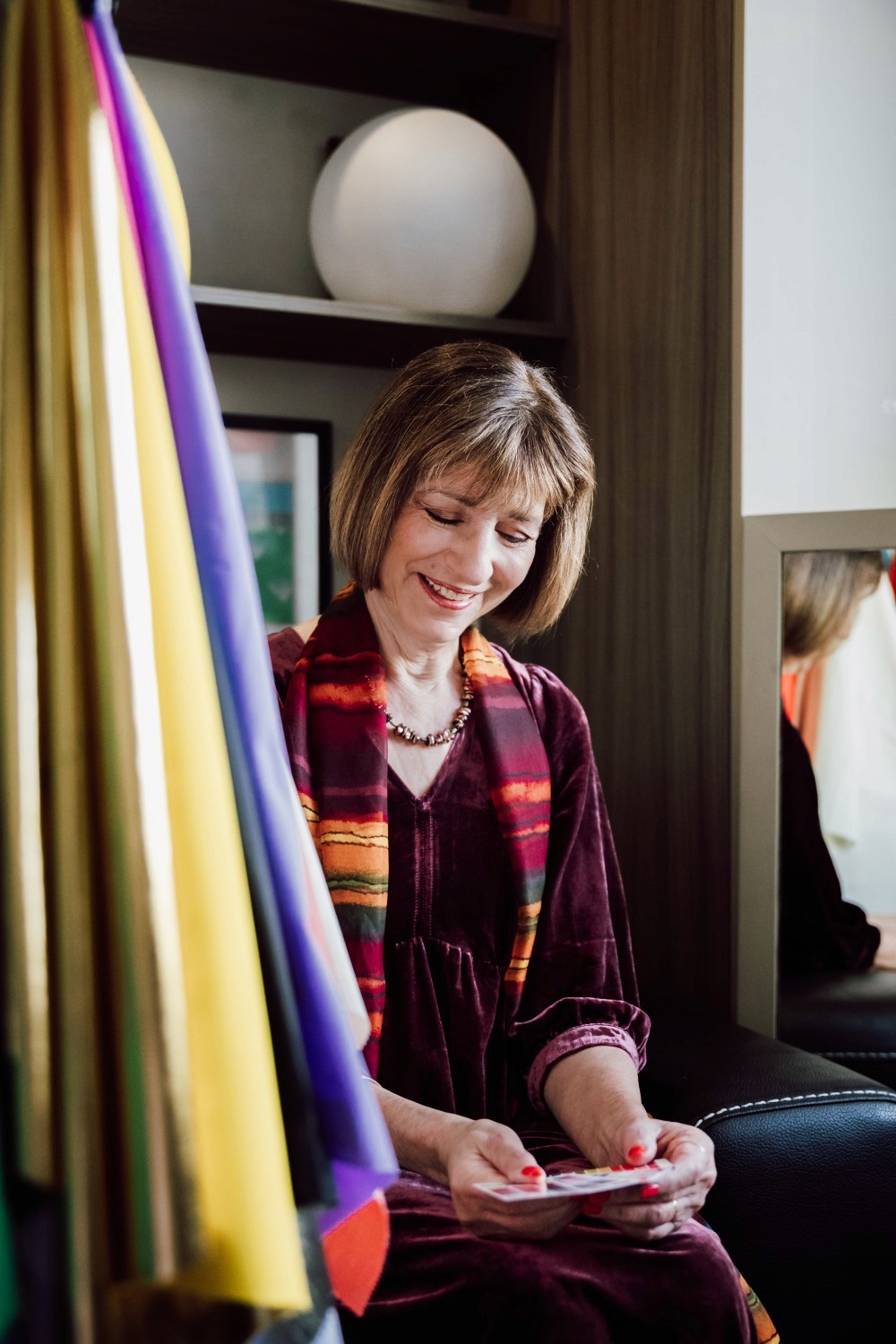 Izzy, smiling next to colour drapes