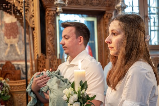 Părinții ținând copilul în brațe înainte de botez, fotografie emoțională de familie.