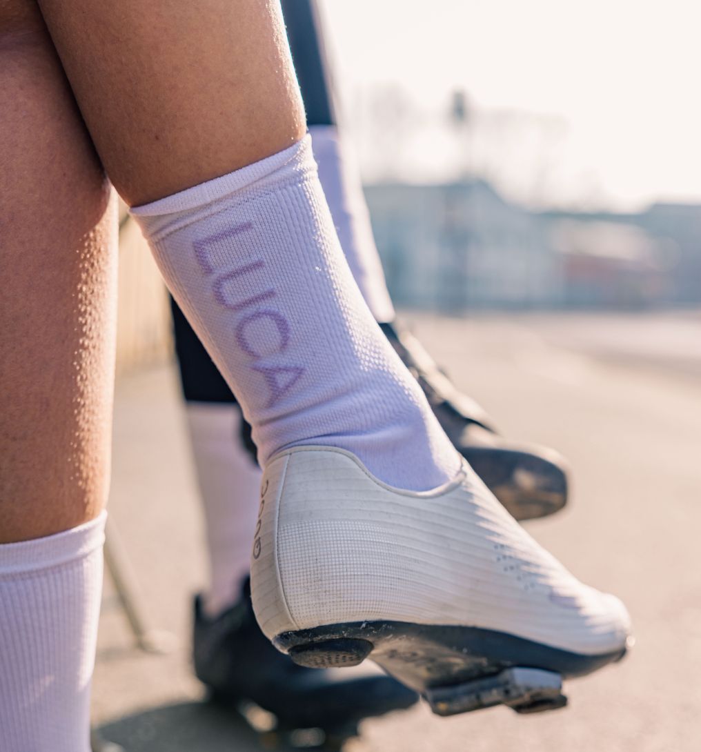 View-of-a-person-sitting-showing- the-fit-of-the-LUCA-cycling-socks- and-white-cycling-shoes