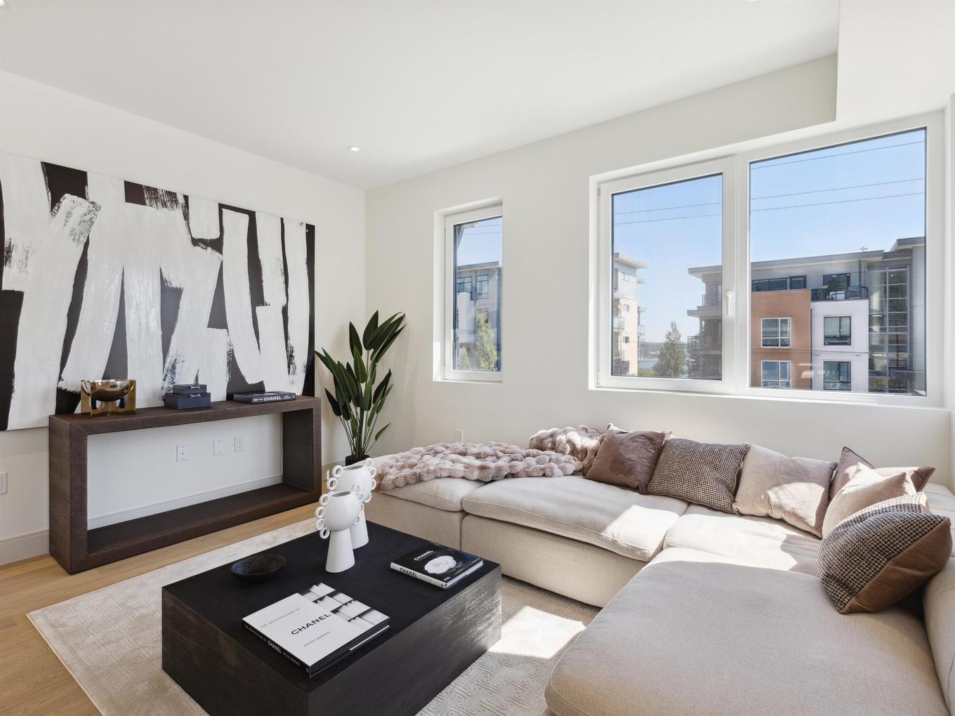 Bright, modern living room featuring a gray sofa, coffee table, and large windows with city views.