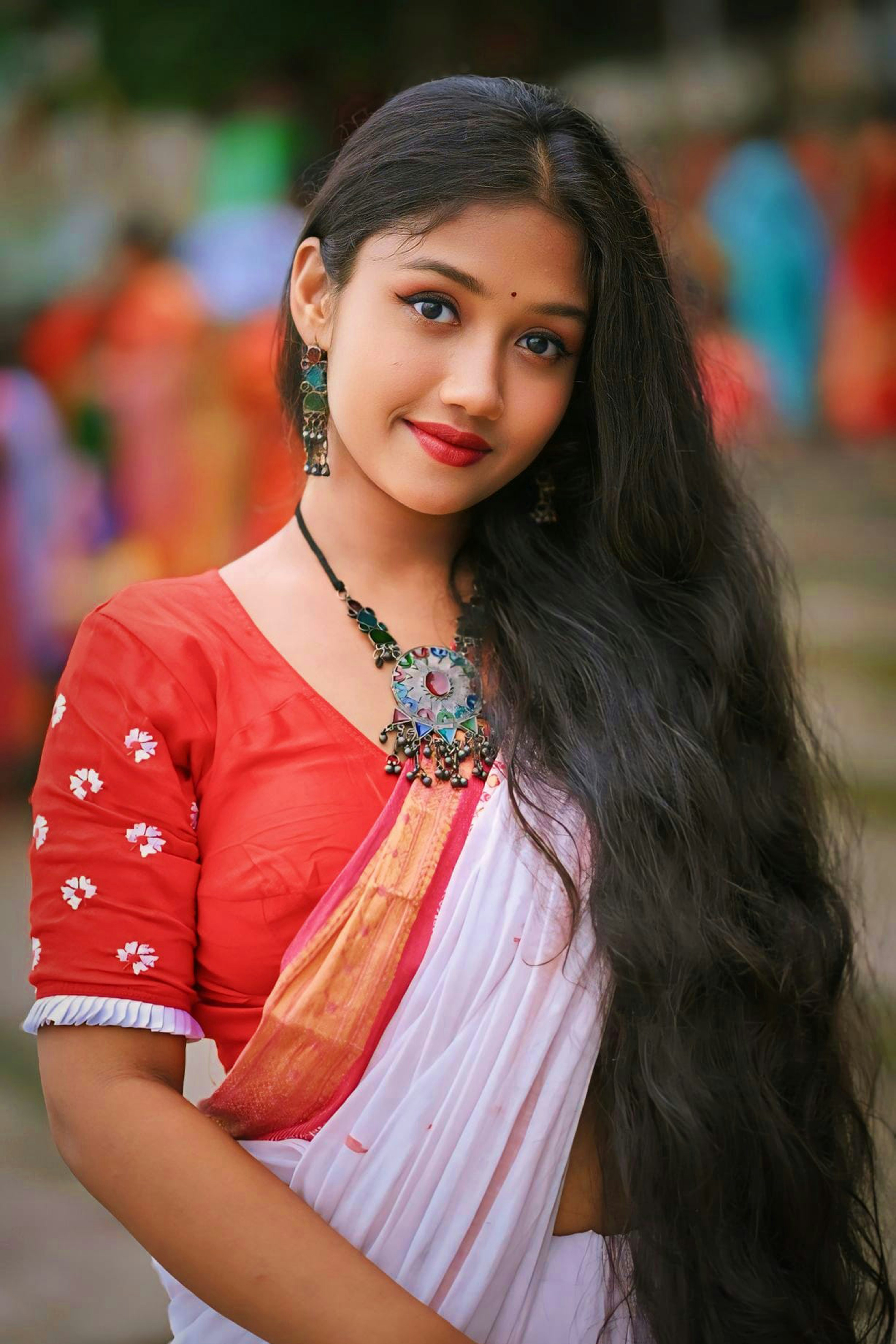 A woman with long hair wearing a red and white sari