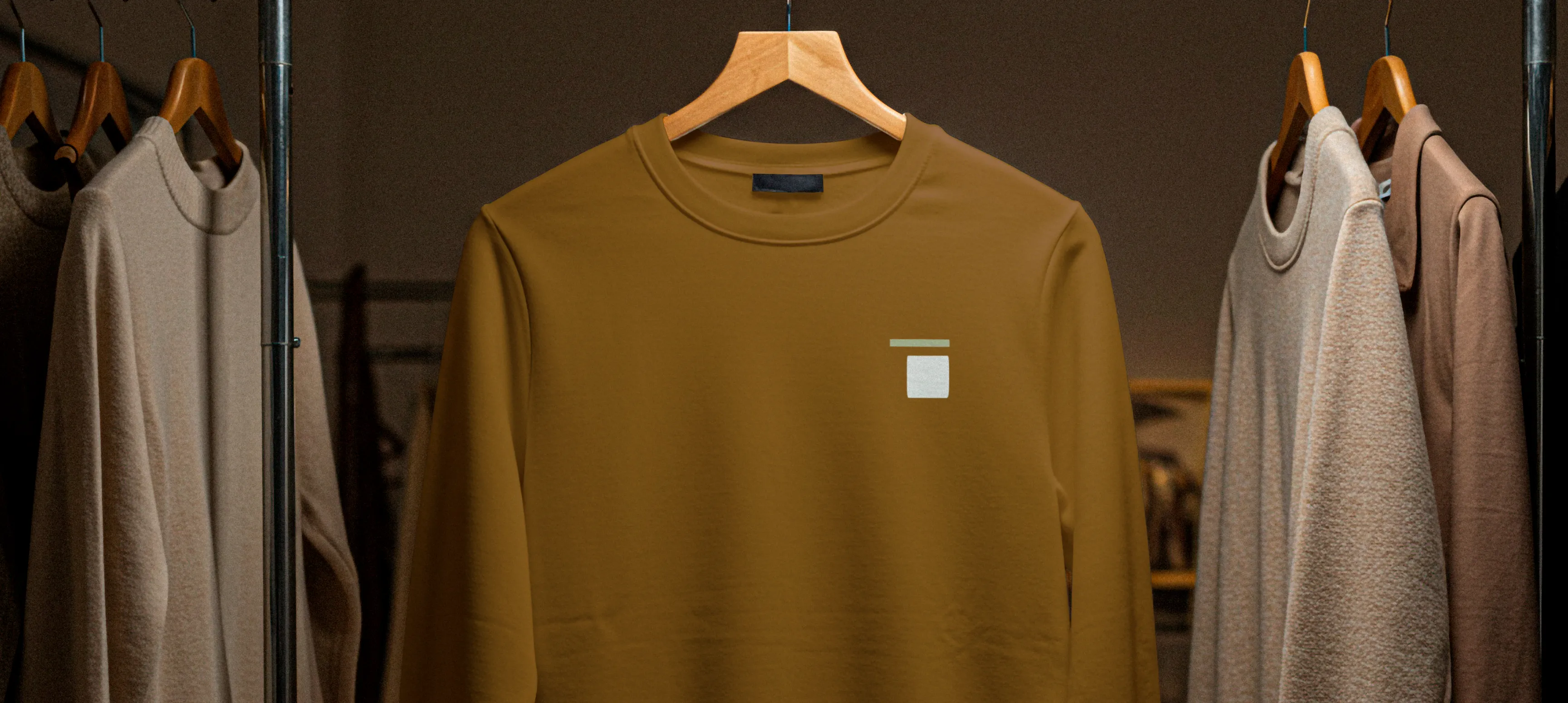Various sweatshirts hanging in a closet. On is displayed facing foreword in a cedar colour and the Coastal Accents icon printed as a pocket print.