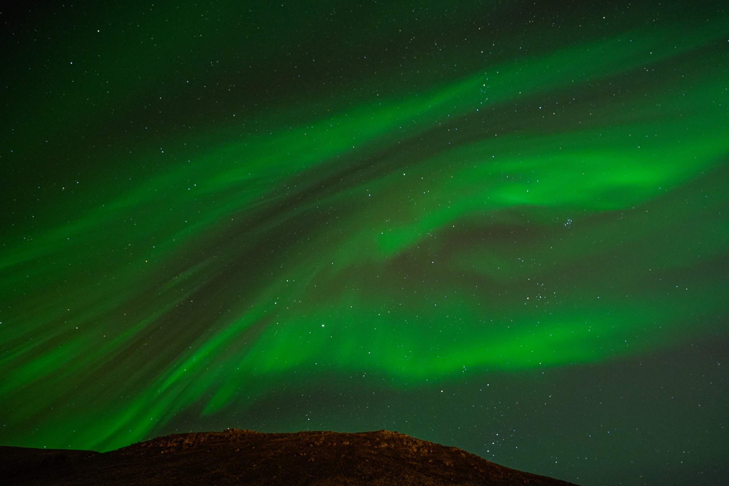 A mountain ridge beneath a full sky of aurora