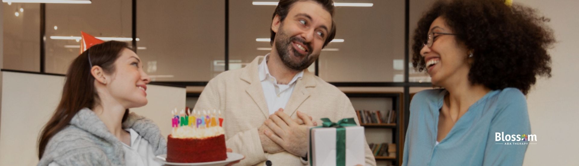 A group of adults at a celebration presents a cake and gifts.