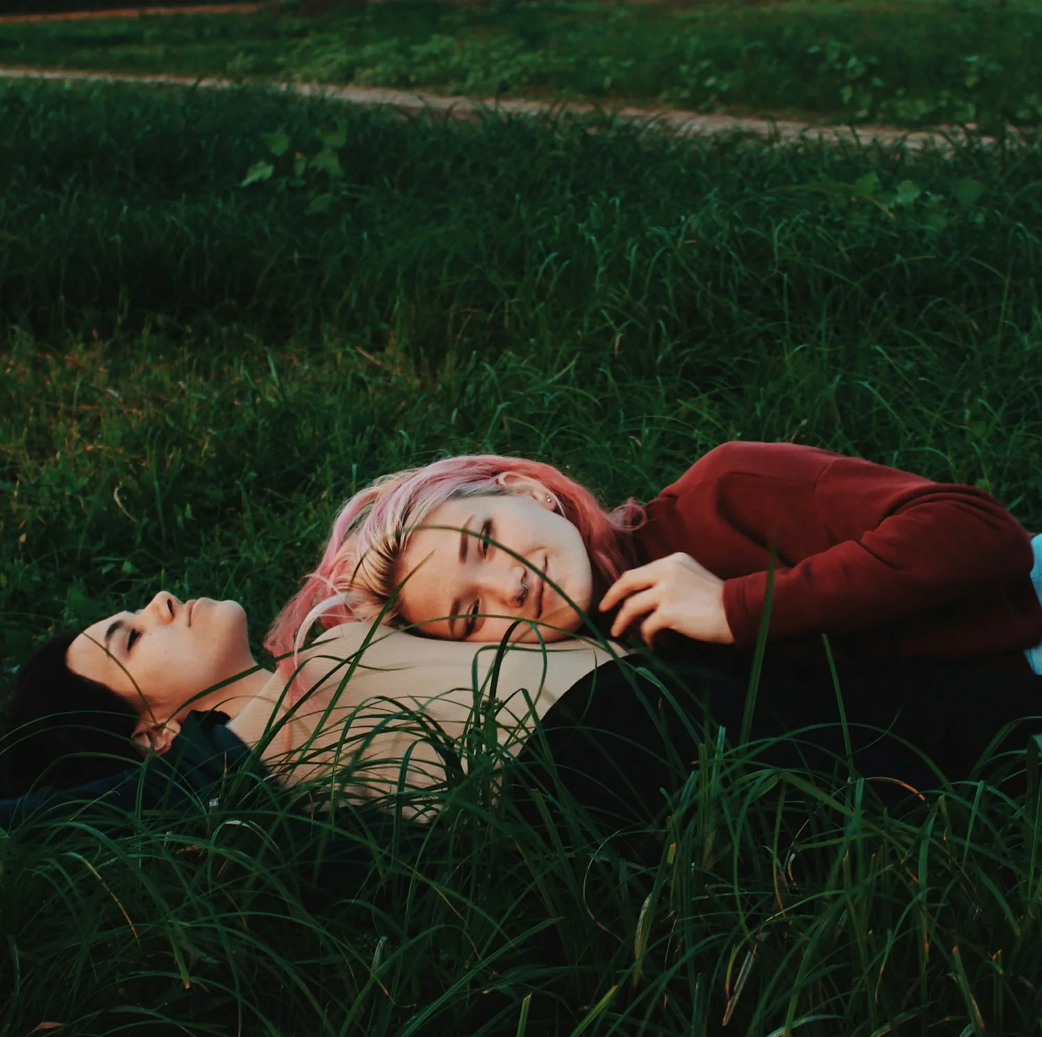 Two women lying together peacefully in a grassy field, symbolizing comfort, love, and connection through lesbian affirming therapy in Los Angeles.
