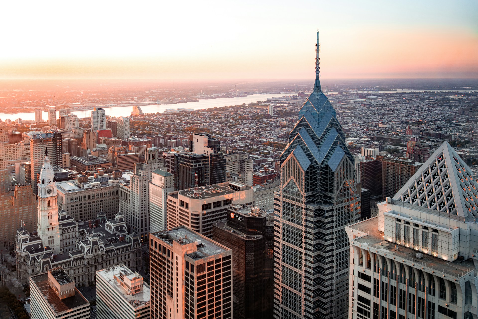 Philadelphia skyline aerial view at sunset with a spired tower and a river beyond.