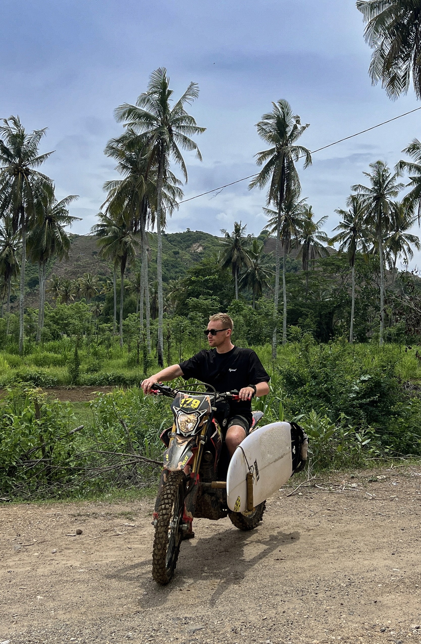 Riding a motocross bike in bali with a surfboard attached
