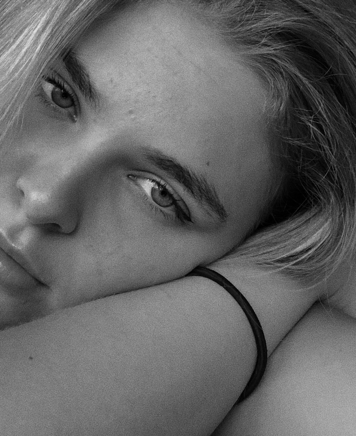 A close-up of a person wearing green-tinted glasses, with a serious expression and smooth skin.