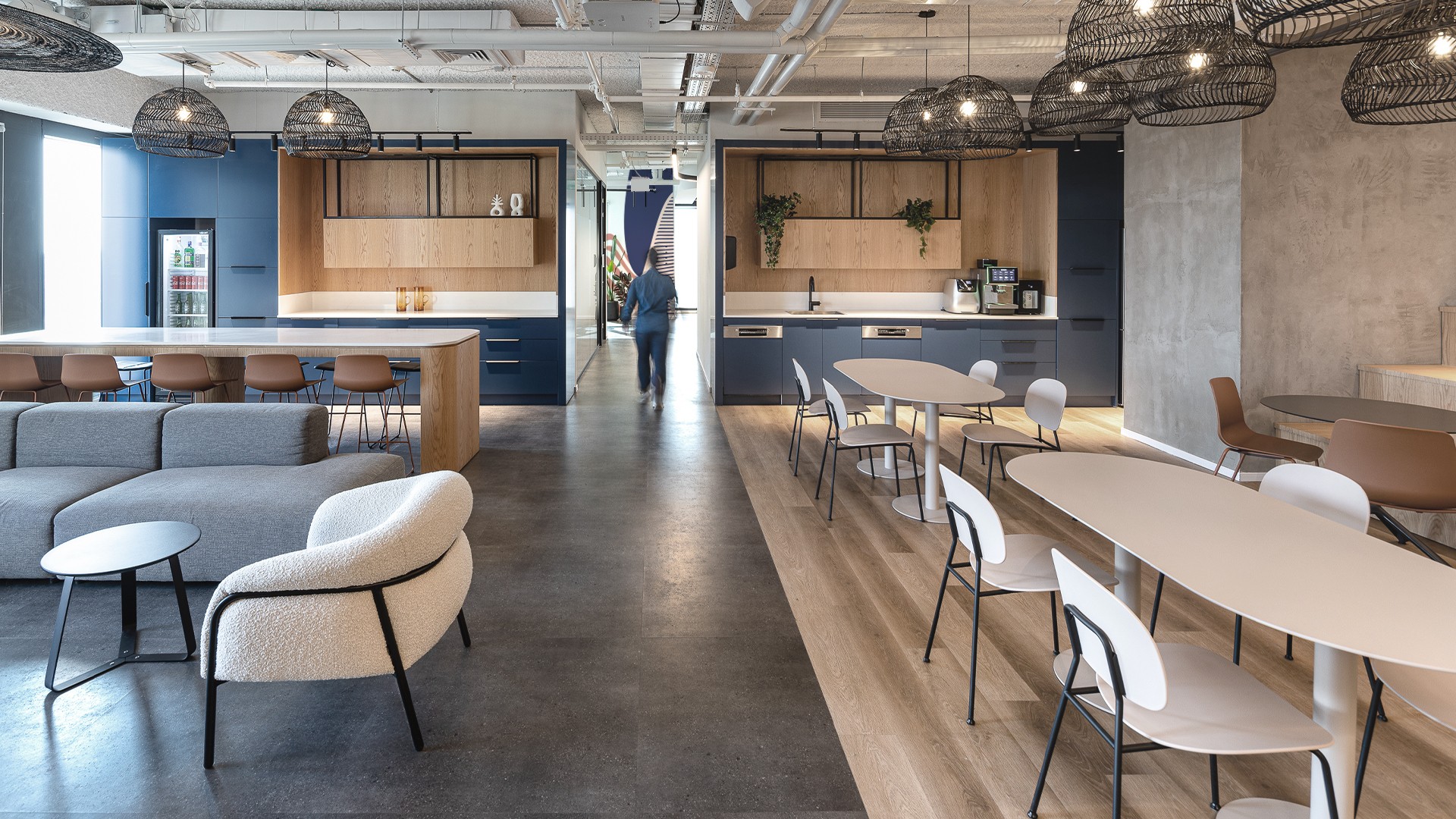 אזור אכילה משותף: שולחן אבירים ארוך מעץ (Communal Table) מתחת לגופי תאורה מרשת, המעודד אינטראקציה חברתית בזמן הארוחות.