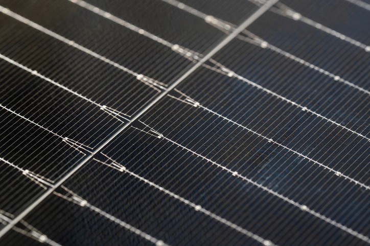 Nahaufnahme von Solarpaneelen mit einem Raster aus dunklen Zellen und dünnen silbernen Linien, die sie miteinander verbinden.