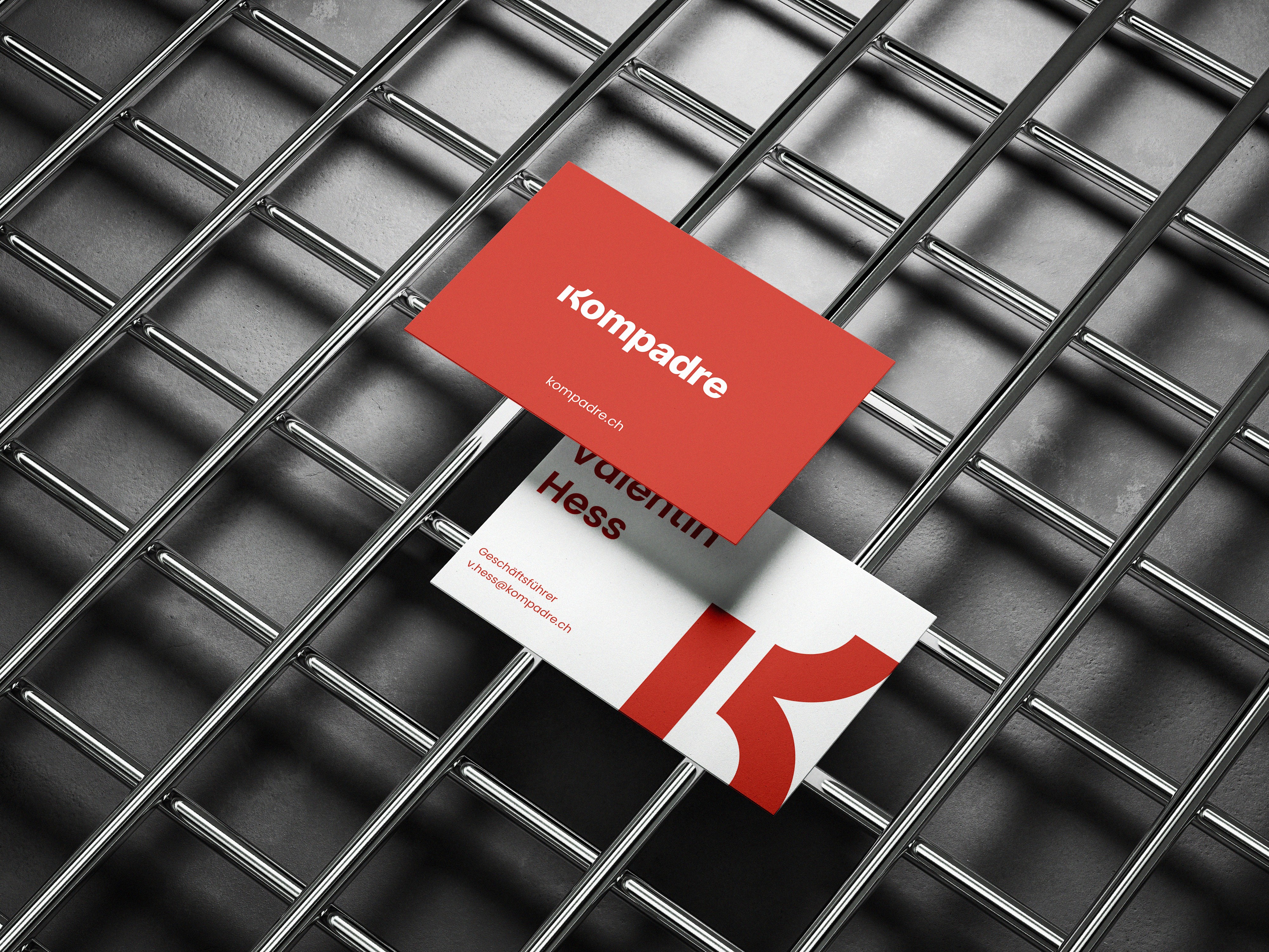 Kompadre Visitenkartendesign mit einem rot-weißen Farbschema, platziert auf einem metallischen Gitterhintergrund.
