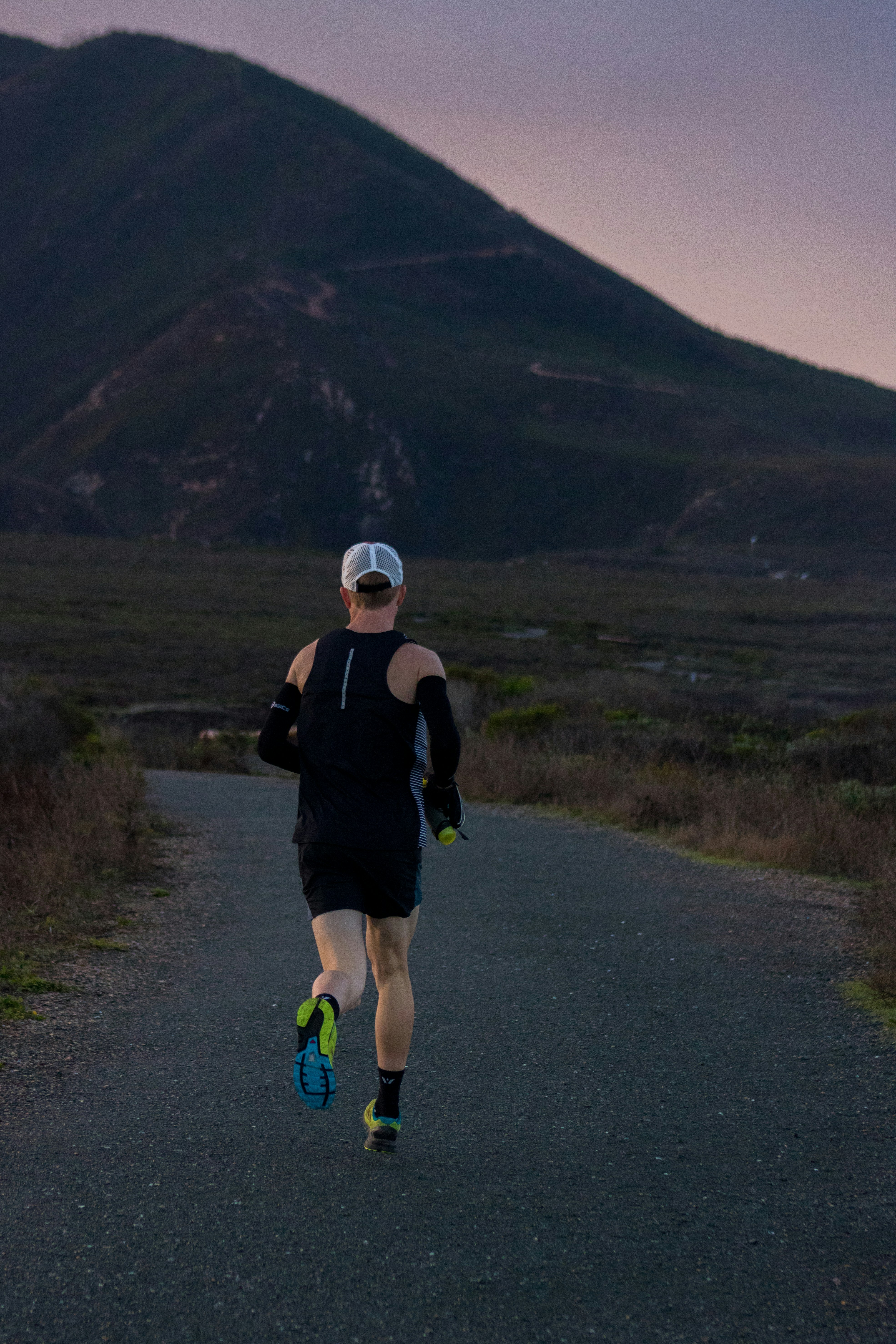 woman jogging on gray road across mountain during daytime