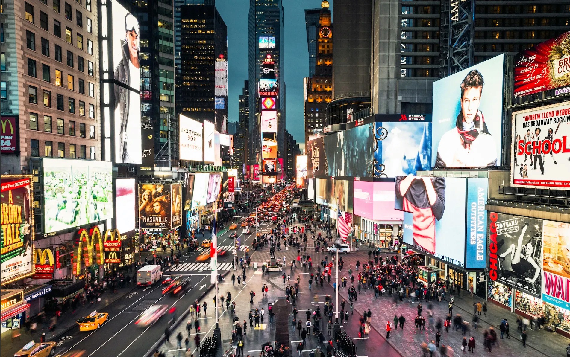 a man walking down a street past a large poster