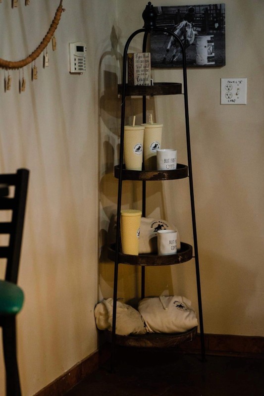 Four vibrant street-style tacos standing upright in hard shells, generously topped with shredded carrots, crispy fried protein, cilantro, and a creamy white sauce, served on a blue plate against a bright teal background.