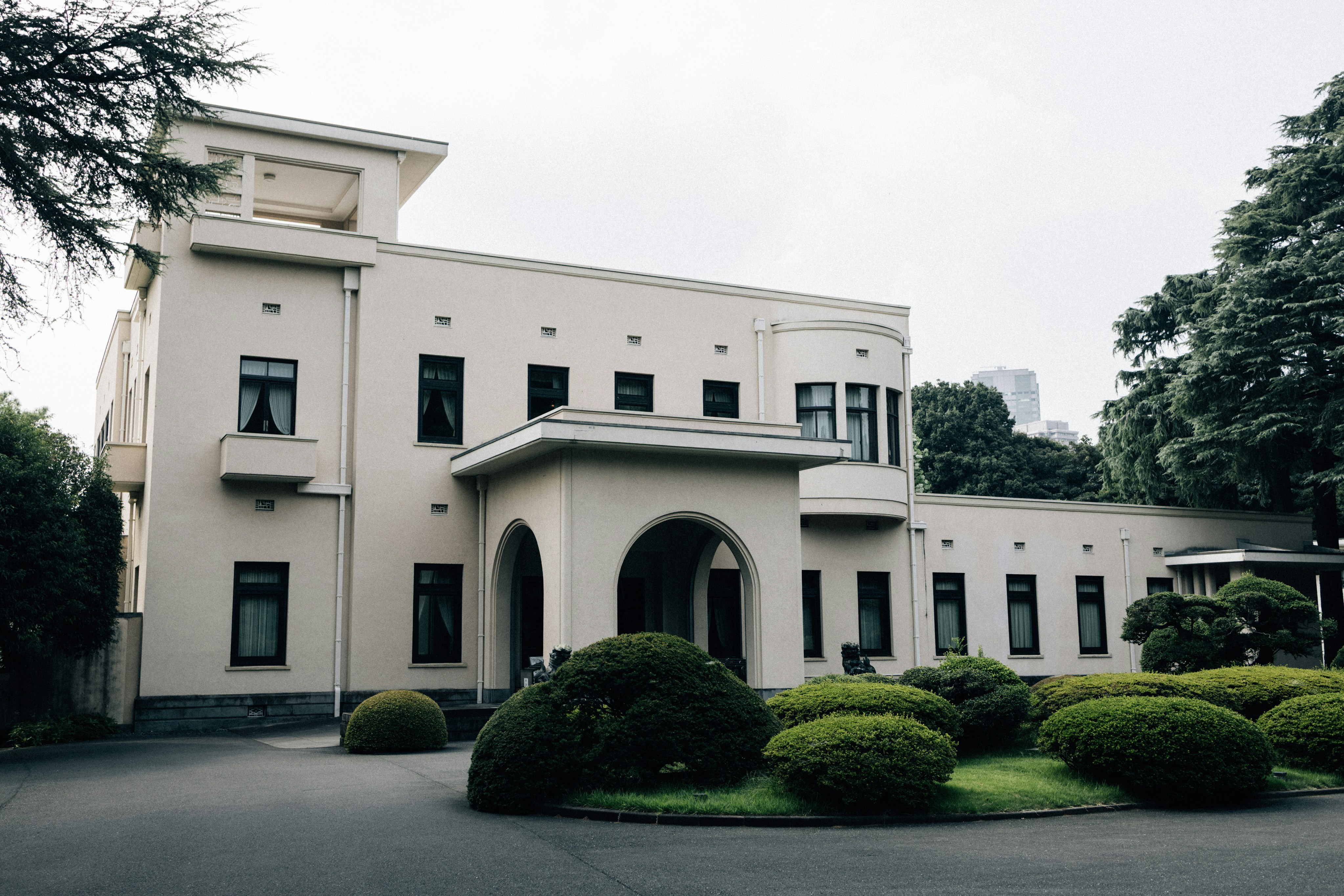 A large white building with manicured bushes in front.