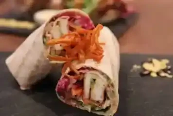 Gegrillter Wrap im kAlps mit Hähnchen, frischem Gemüse, Sauce und knusprigen Röstzwiebeln.