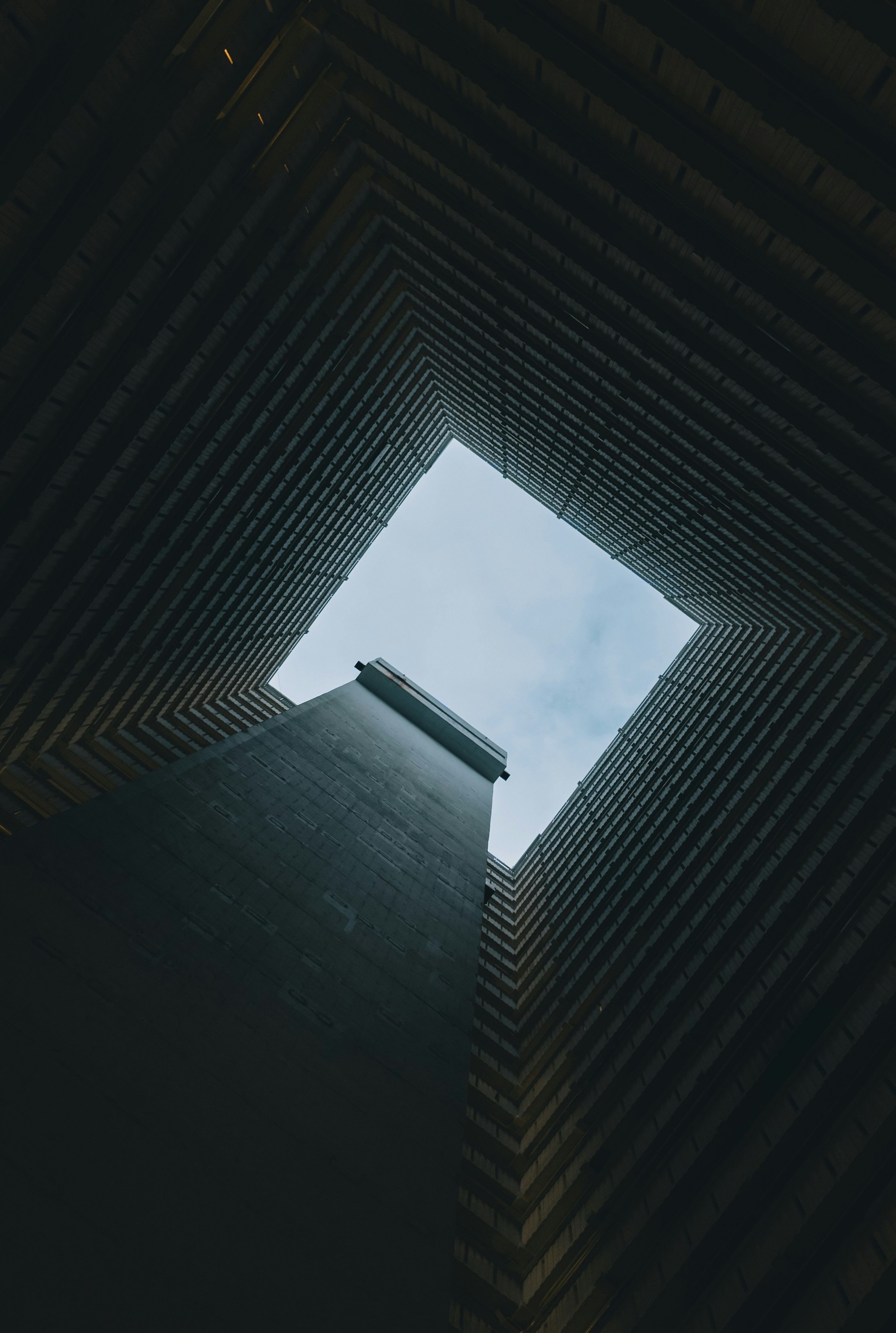 Looking up through a concrete building shaft to sky