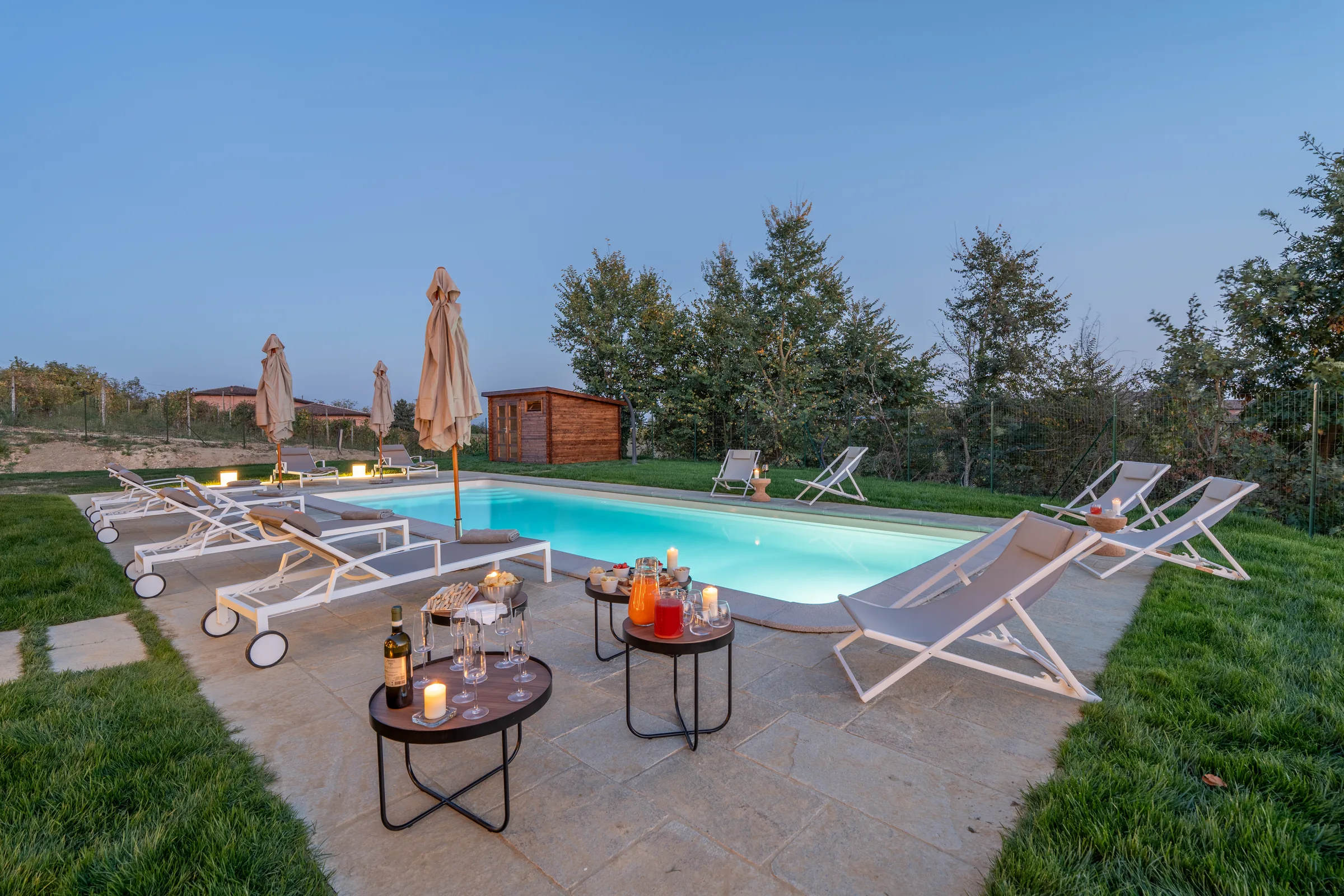 Outdoor dining area overlooking the pool at sunset — Fubine Monferrato, Italy. Photography by Yunes Calore.