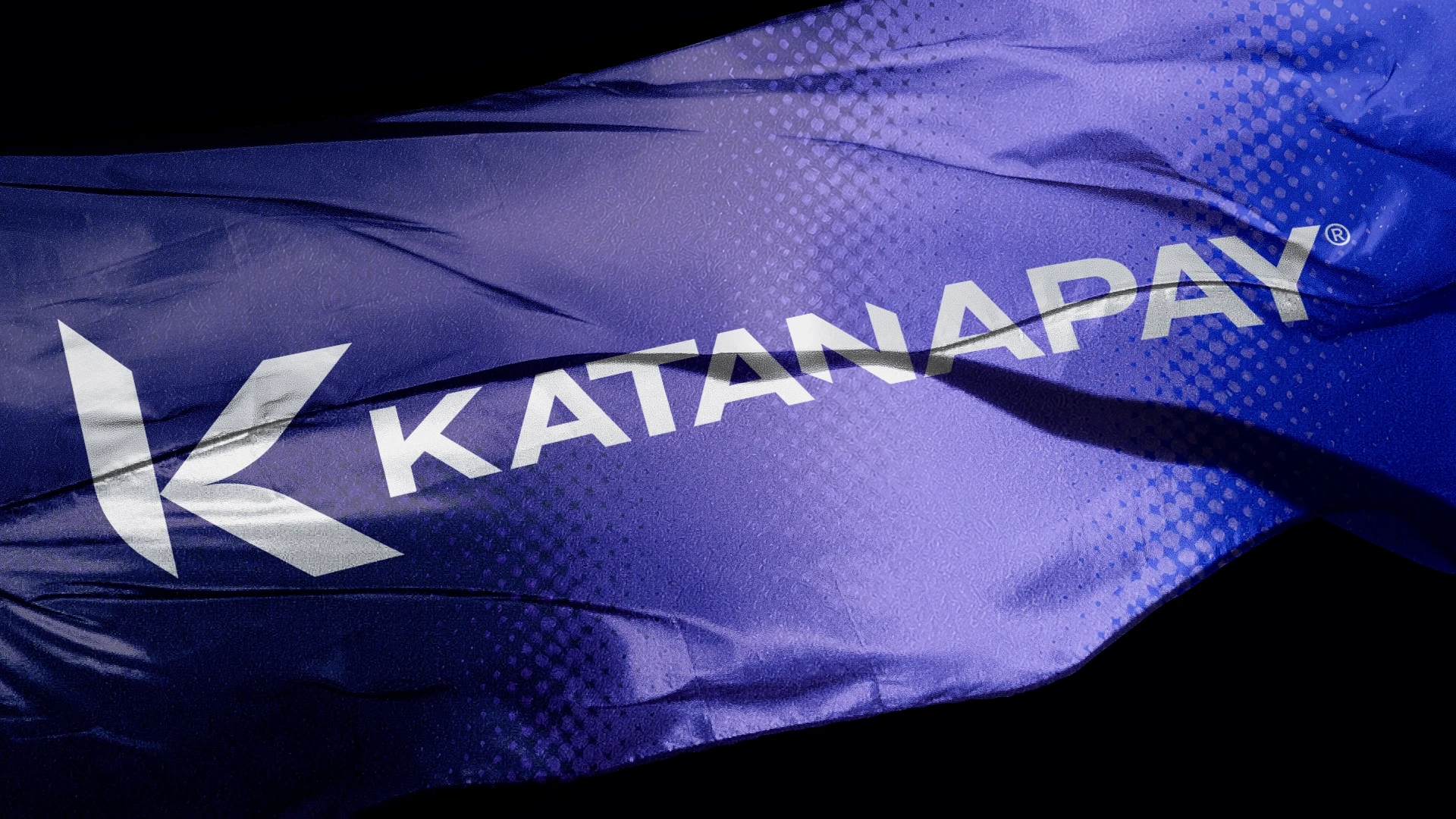 Close-up of a rippling blue-purple KATANAPAY flag with bold white logo and lettering, conveying energy, movement, and a dynamic tone.