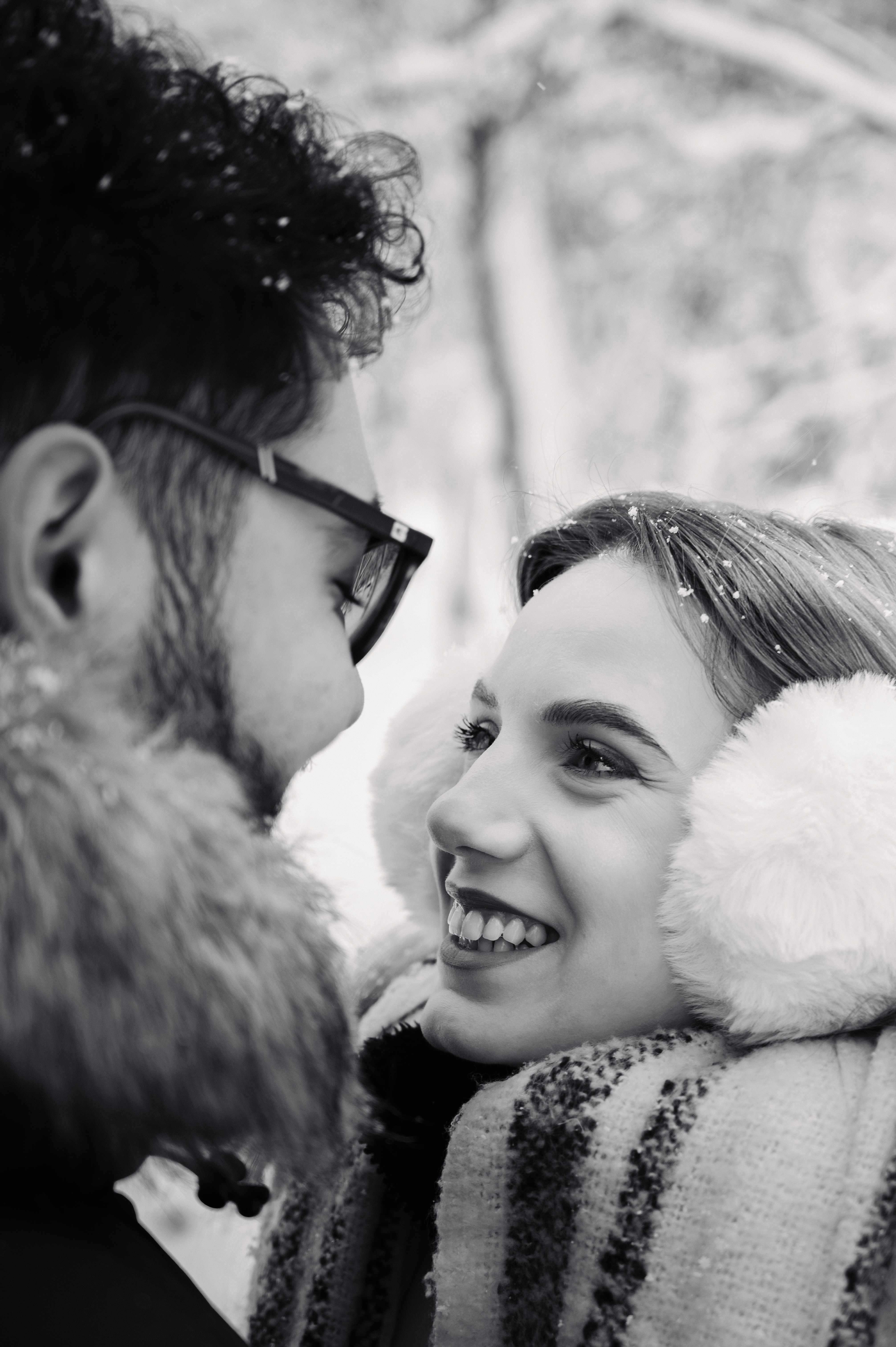 Portret alb-negru cu un cuplu în ședință foto Save the Date, surprins în zăpadă, cu expresii naturale și emoție autentică