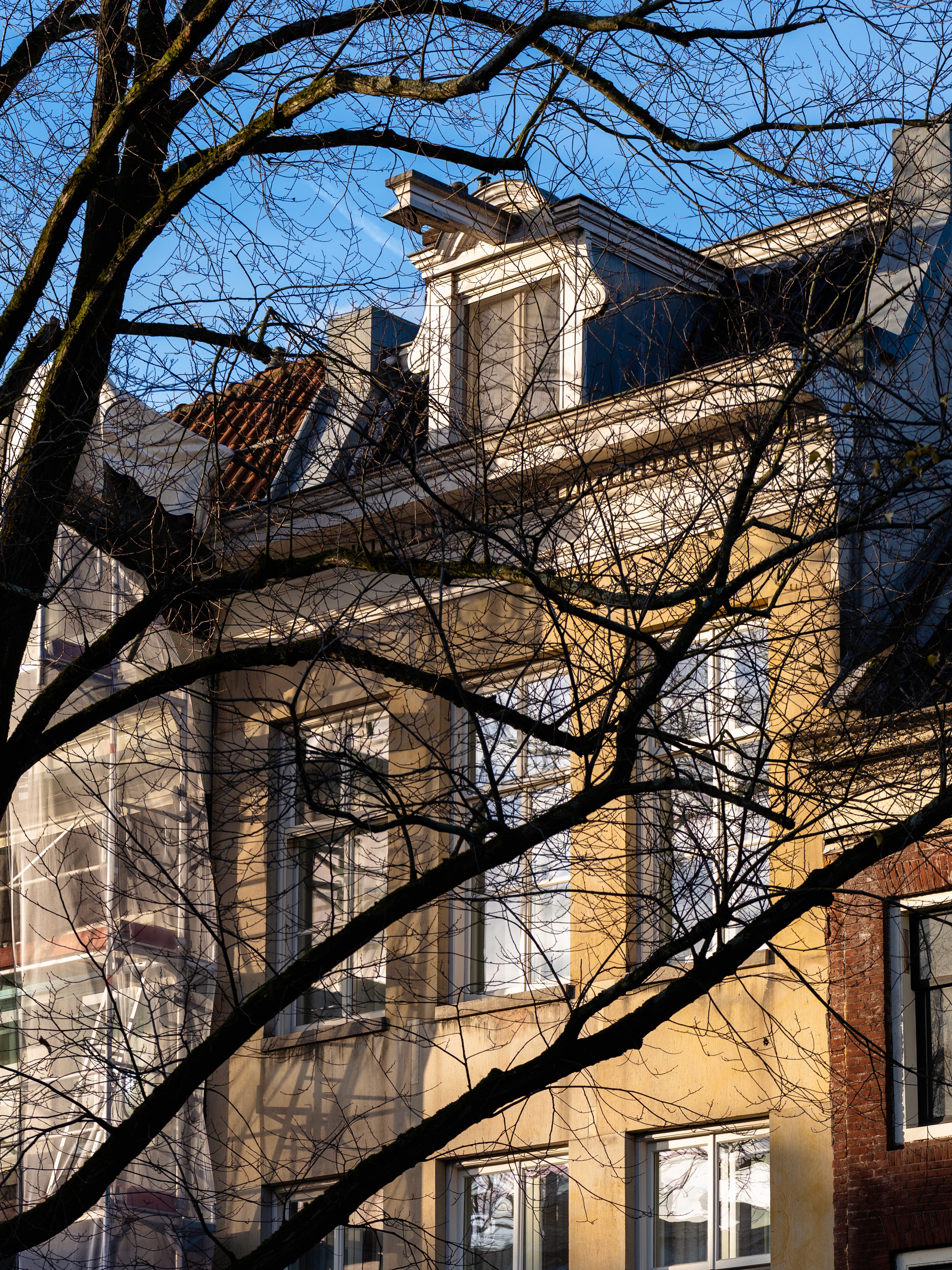 Sunlit canal house in Amsterdam, with warm yellow sun rays on a cold winter day.