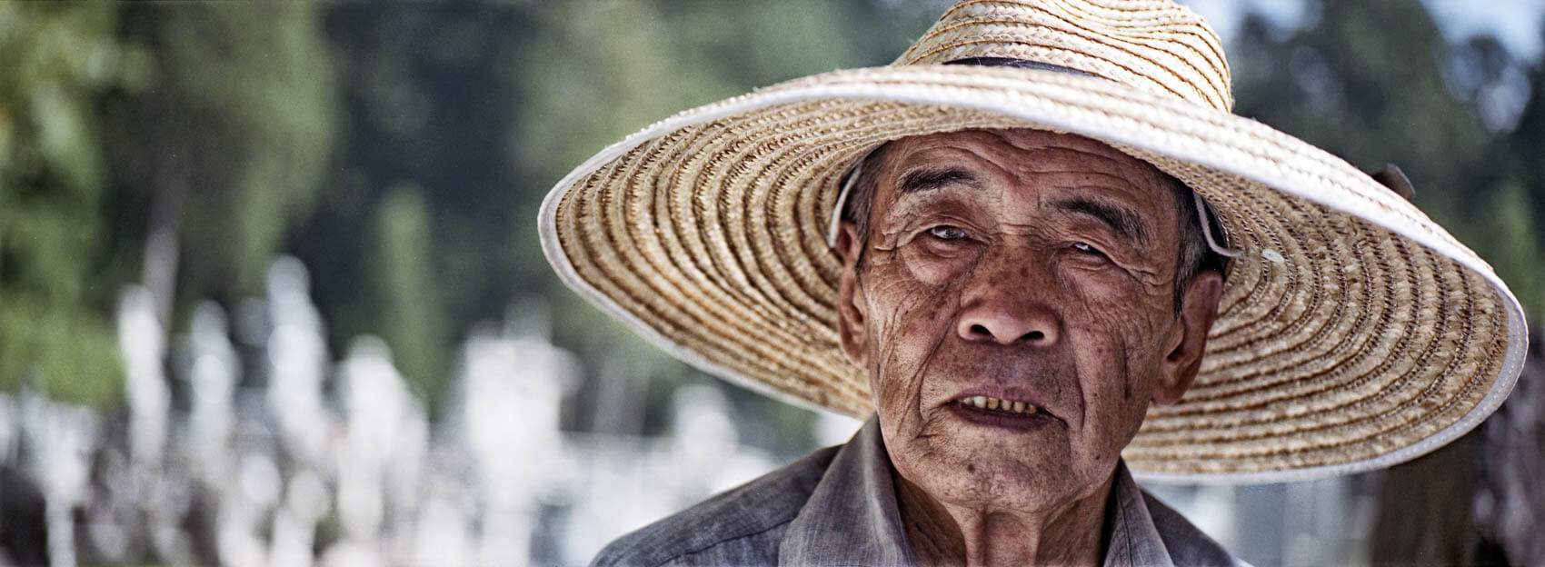 Fujifilm TX-1 panoramic photo of a farmer in Japan, with afternoon light and strong use of depth of field.