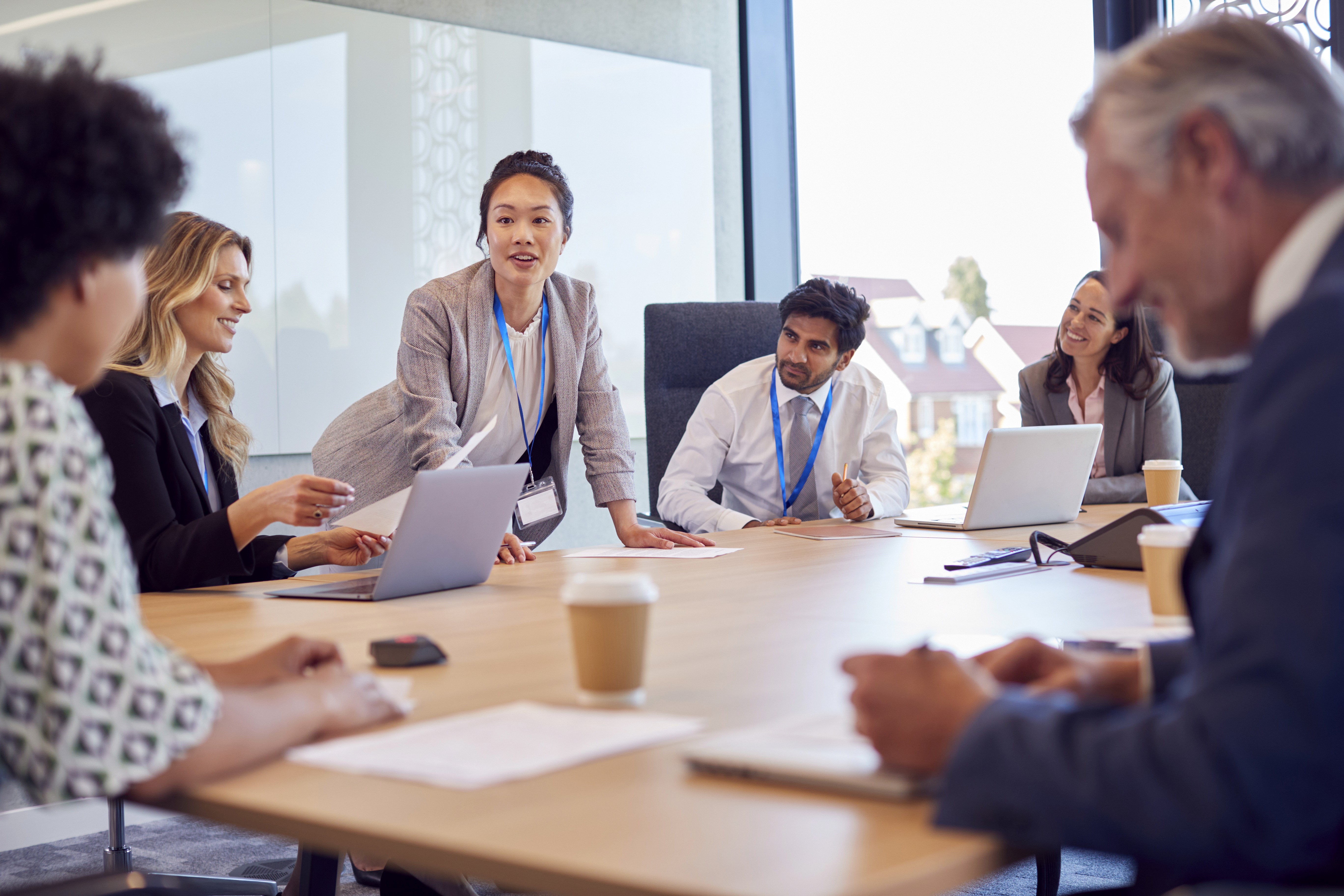 four people watching on white MacBook on top of glass-top table