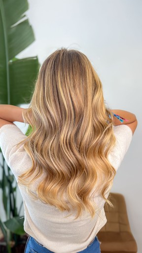 A woman lying down with a towel wrapped around her head, her face glistening with facial oil. Her eyes are closed, and she appears to be enjoying a spa treatment in a peaceful setting.
