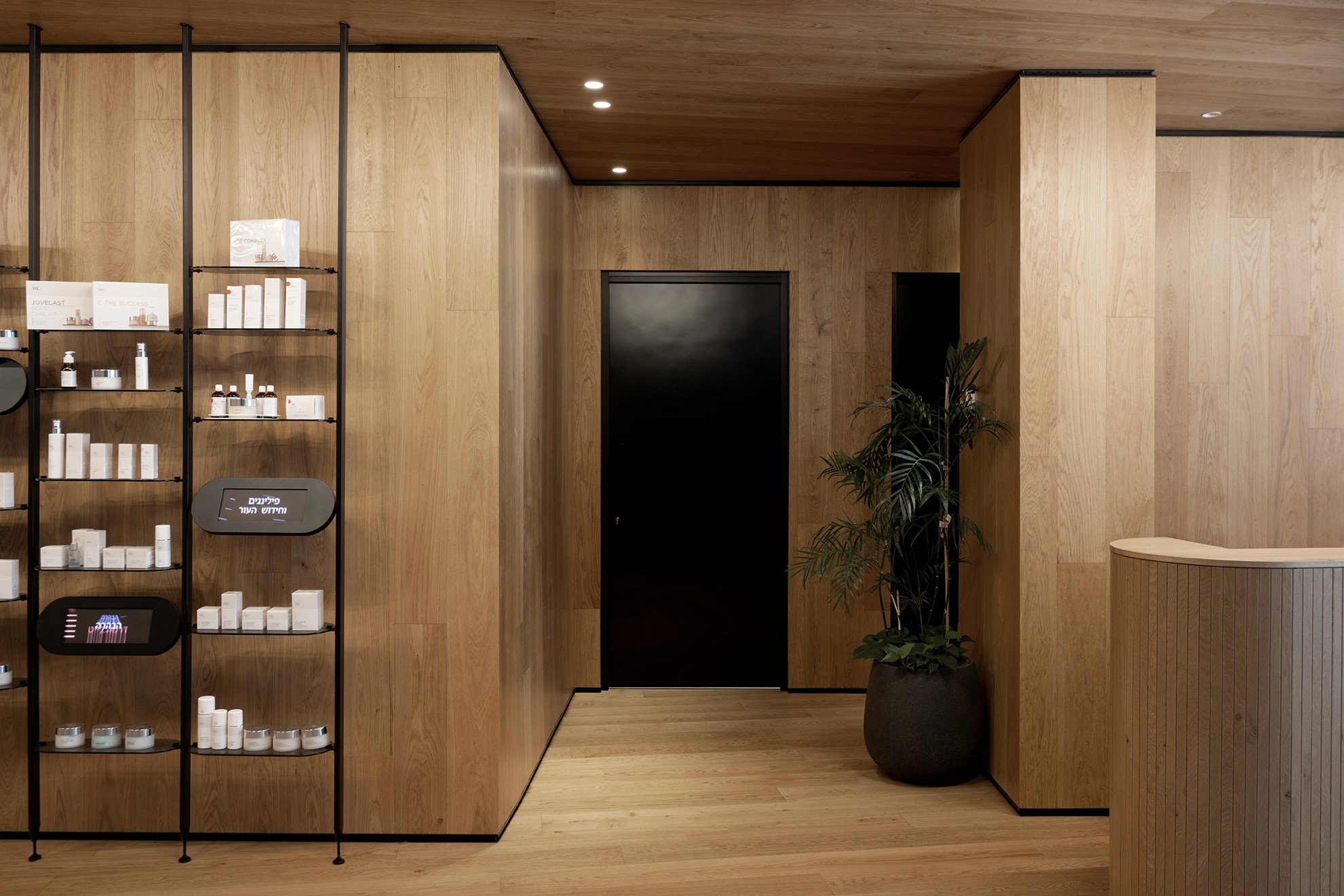 פרטי גמר ונגרות: מעבר בין חללים עם חיפוי עץ מתמשך (Continuous Wood Cladding) ודלתות שחורות בקו-אפס, ליצירת מראה אחיד ונקי.