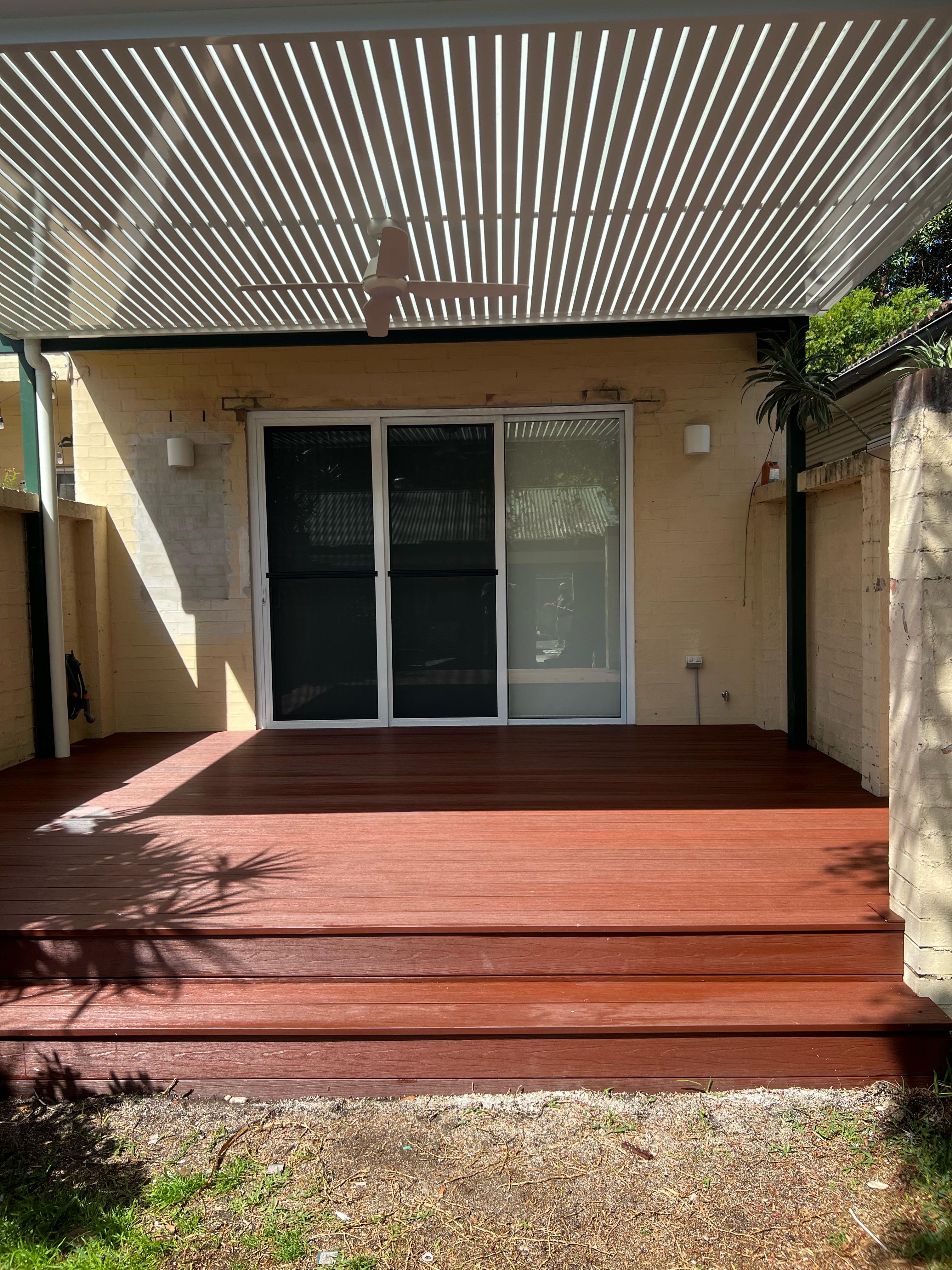 Timber decking with modern white pergola and aluminium sliding doors creating an outdoor living space.of modern pergola with white posts, providing durable outdoor shade and low-maintenance backyard cover