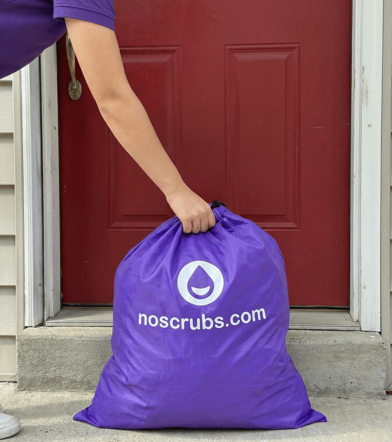 NoScrubs delivery partner collecting a purple laundry bag from a customer’s front door