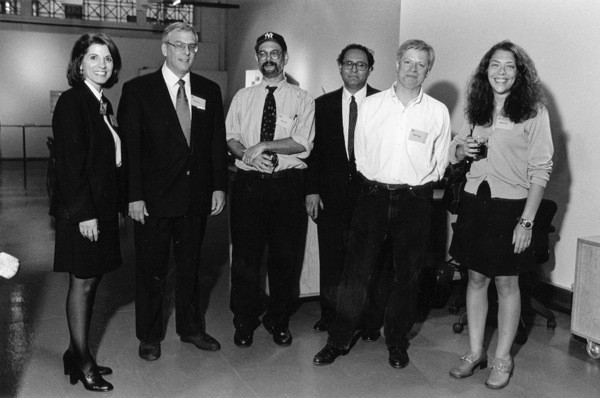 A black and white photo of a group of people standing in a hallway.