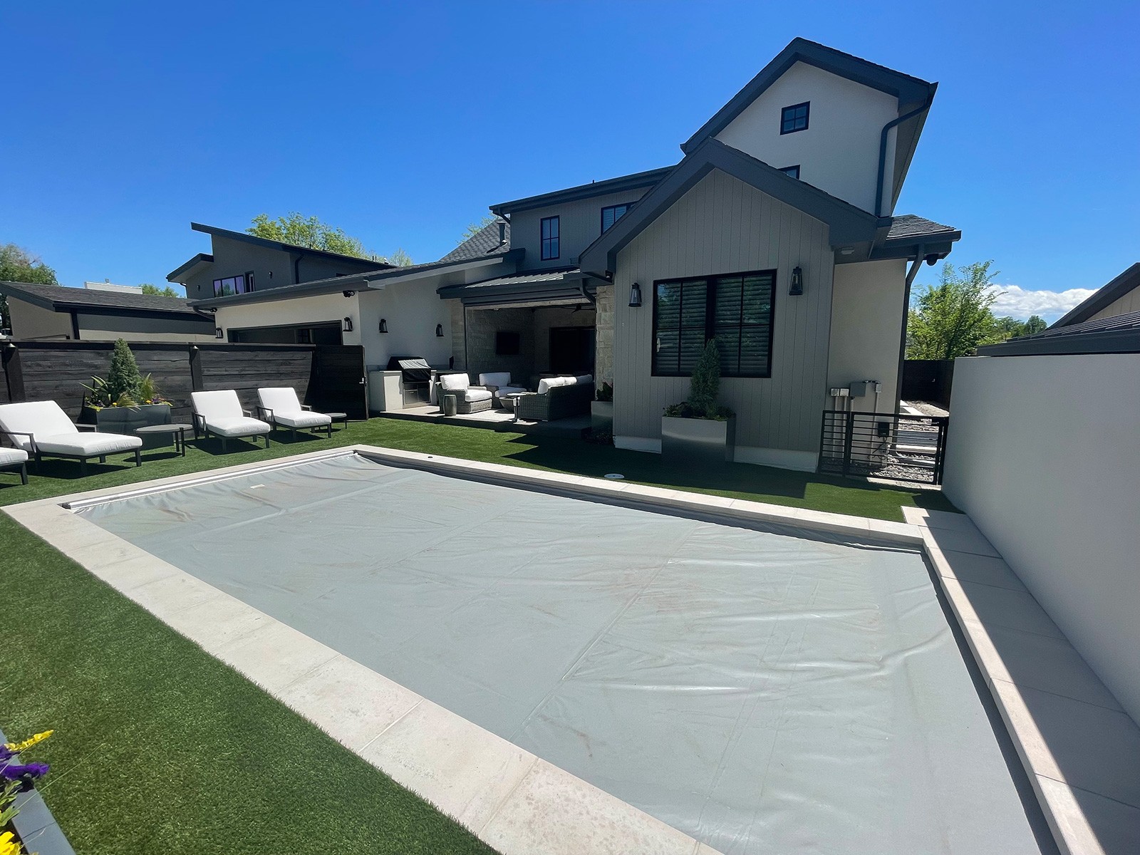 outdoor pool surrounded by artificial grass, a white and grey house, backyard in Parker, Colorado, blue sky