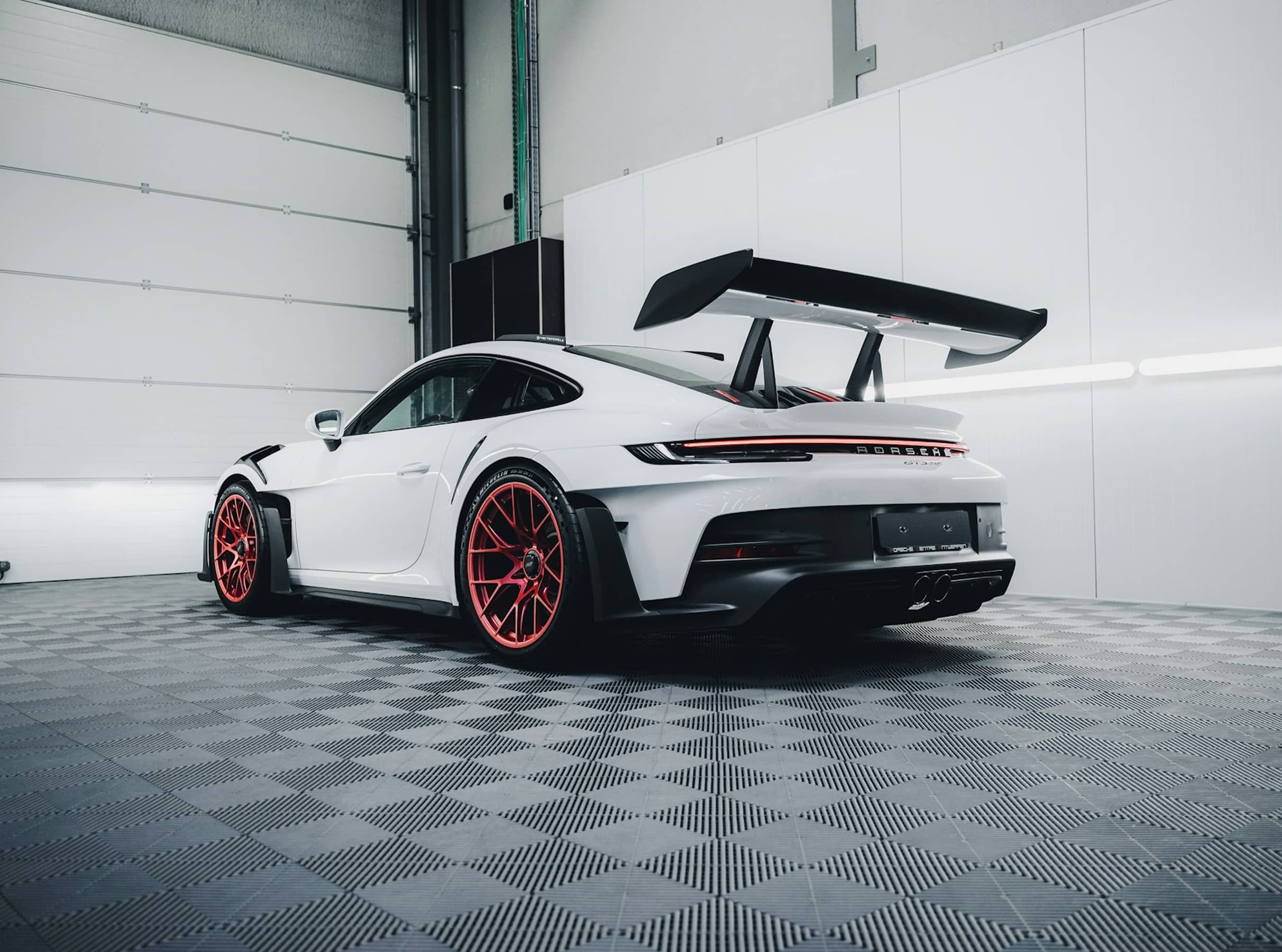 White sports car parked inside a modern auto repair garage.