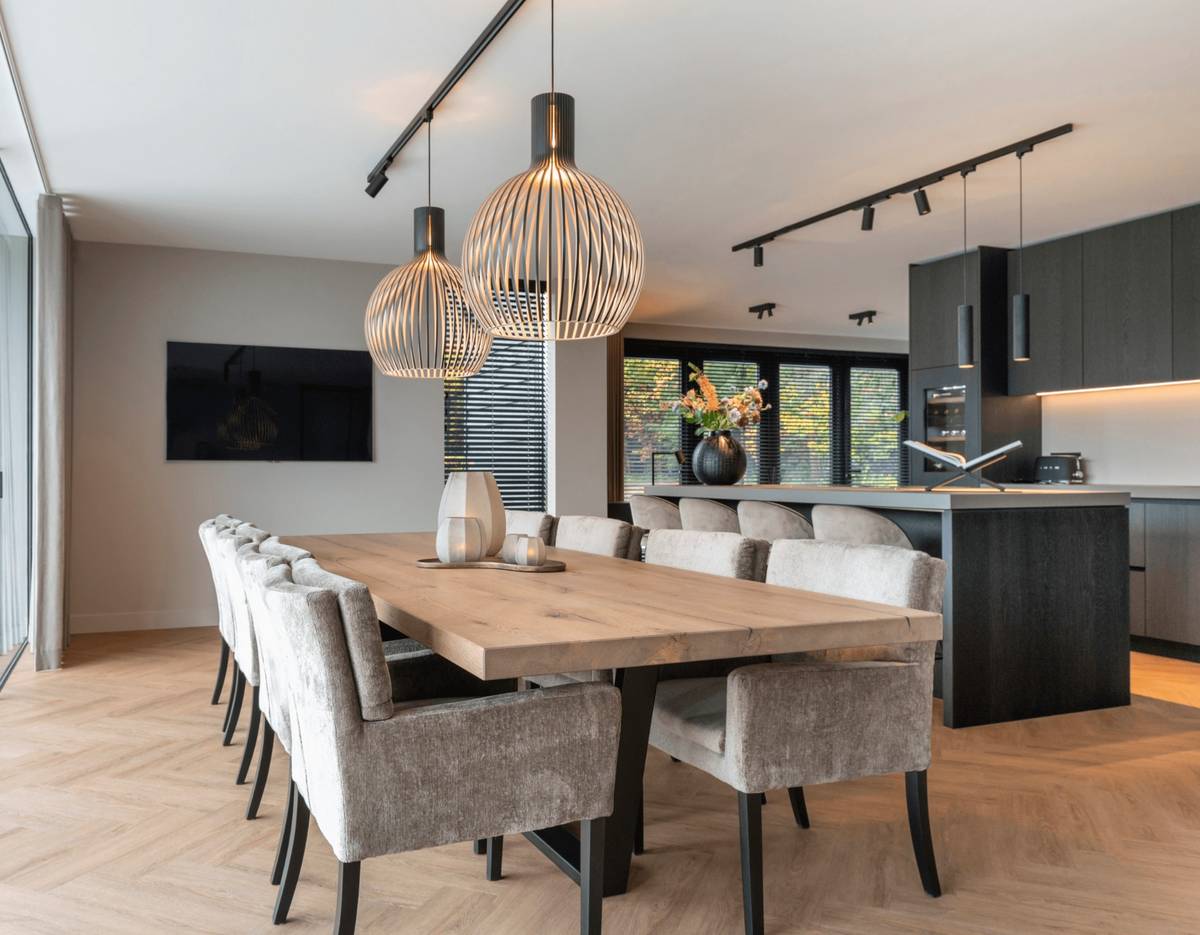 woonkeuken landelijke villa zwarte keuken en boomstamtafel met velours stoelen