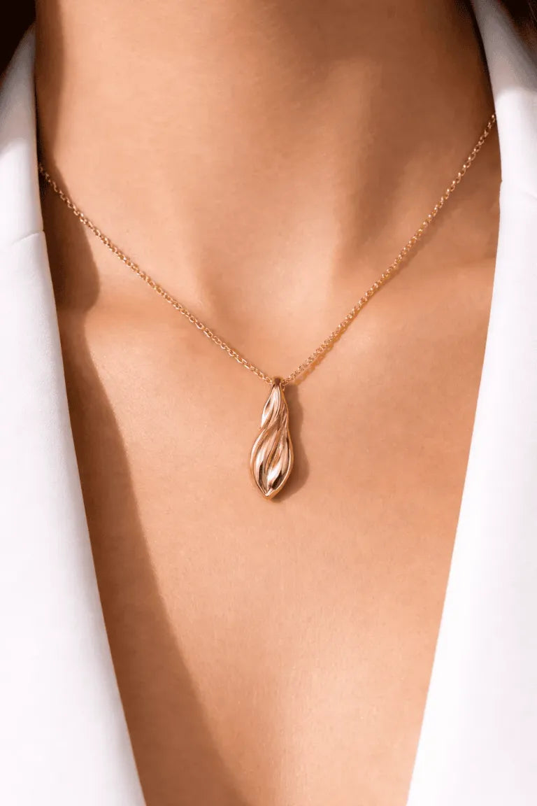 Gold necklace with a pendant on a person's neck against a white background