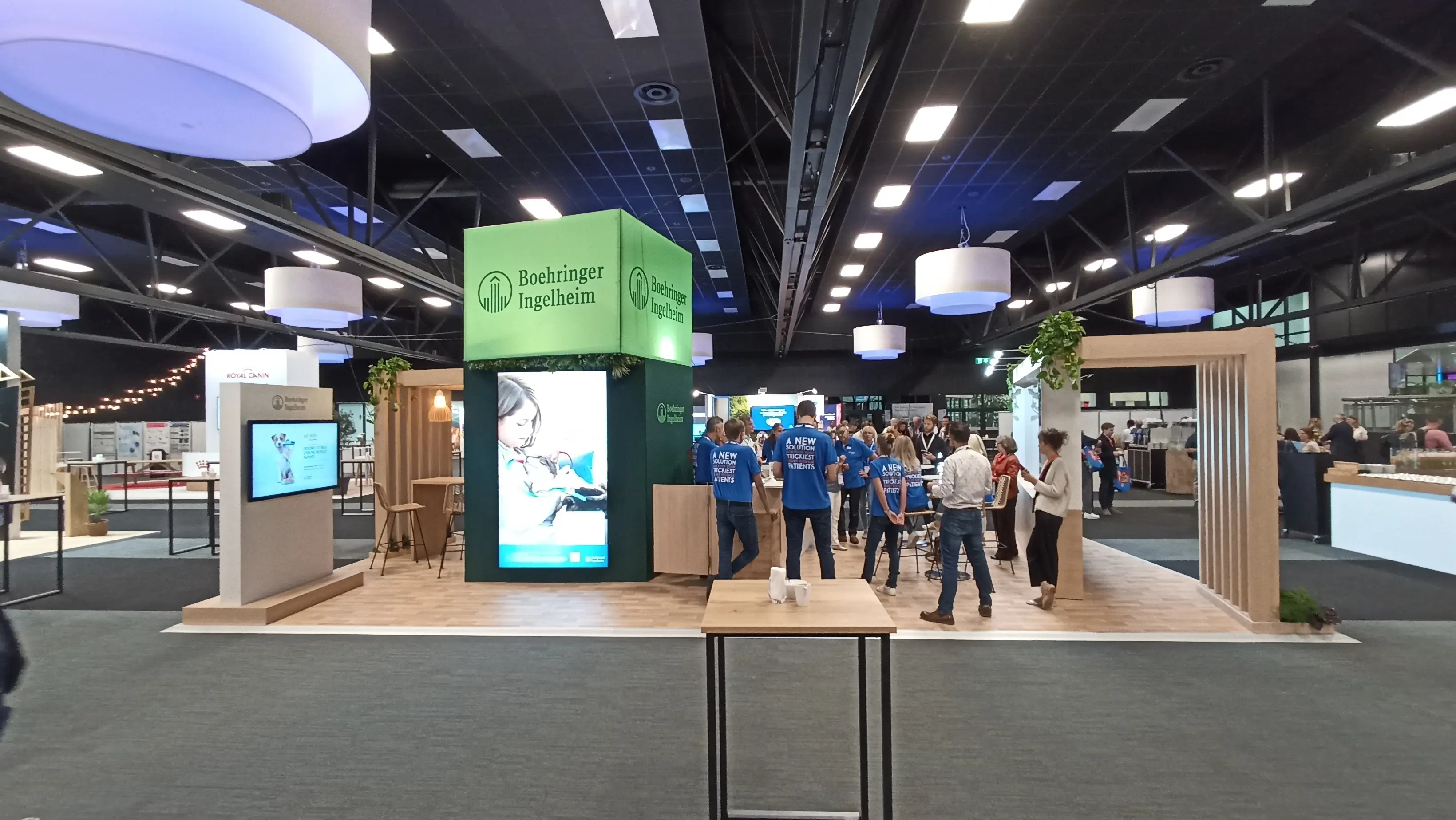  Vue générale du stand Boehringer Ingelheim conçu par Expace à l’ECVIM, avec totem lumineux vert et espaces d’échange en bois