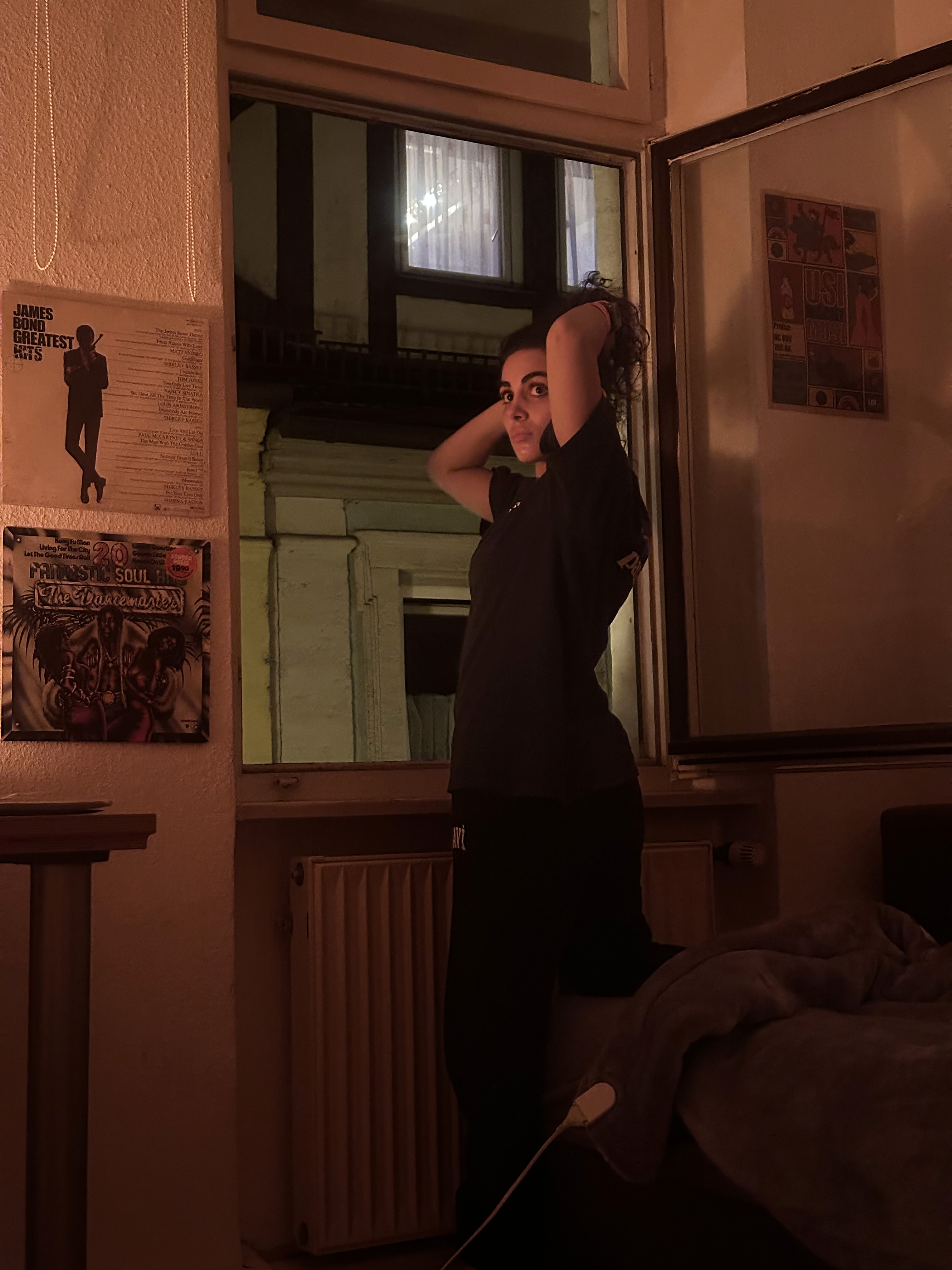 Green car under neon lights in a rainy city street