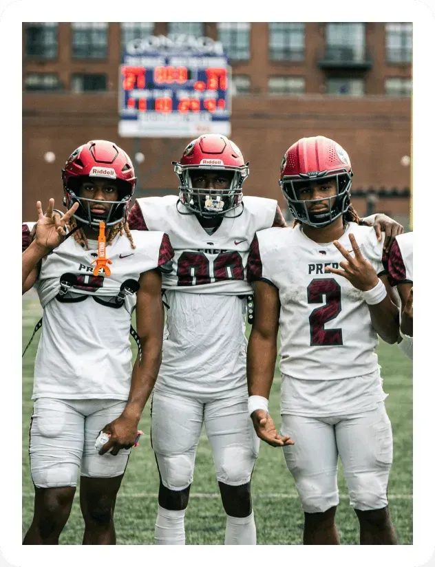Three football players posing together on a field.
