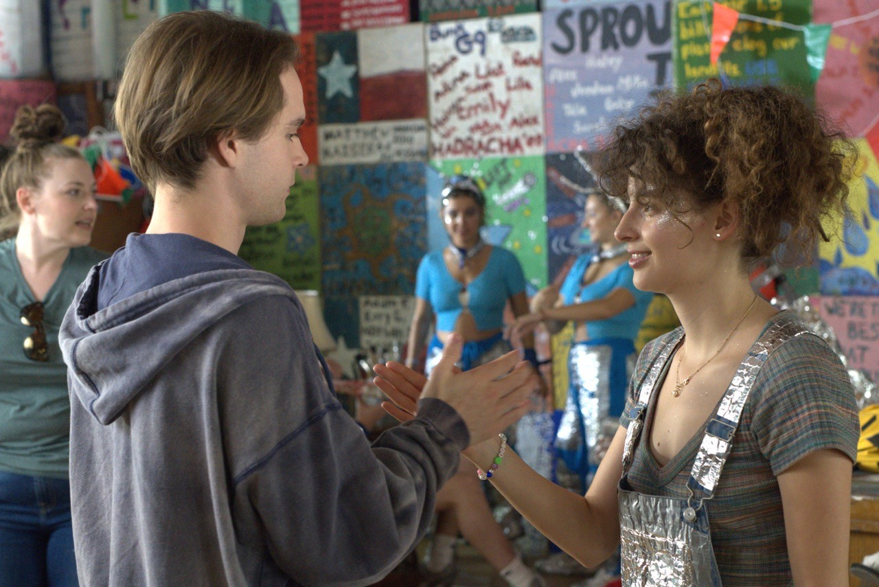 Still from The Floaters: Two young people stand facing each other, smiling and playing a hand-clapping game.