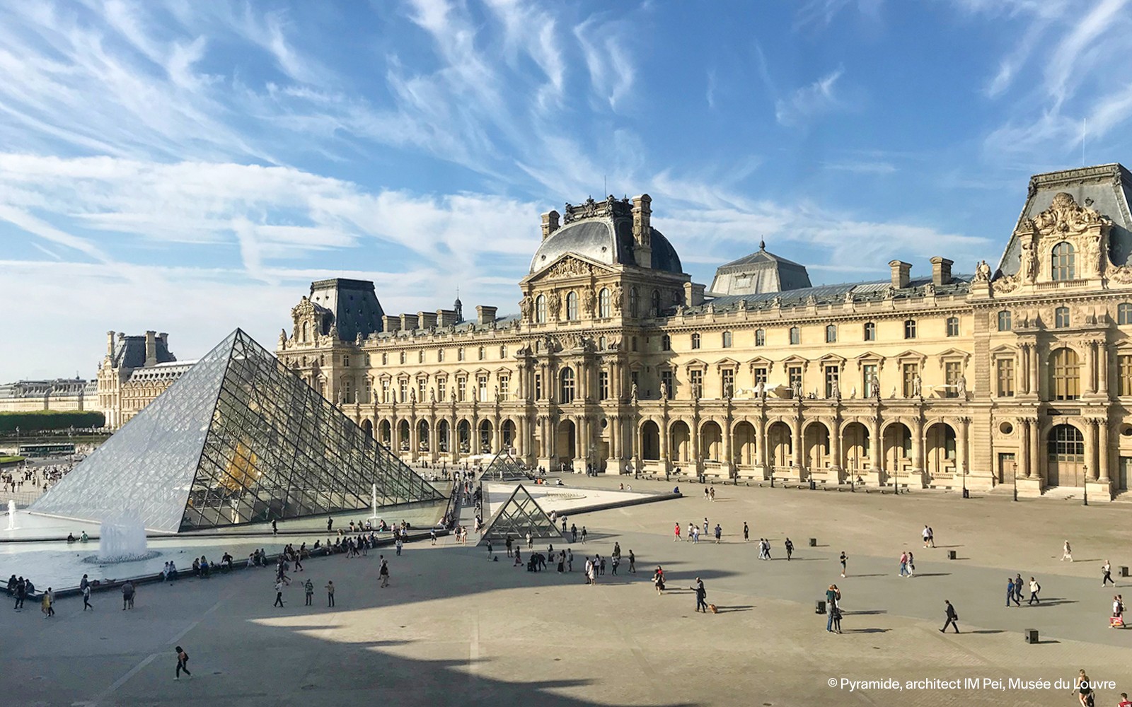 Personas caminando cerca de la pirámide de cristal del Louvre en París, Francia.