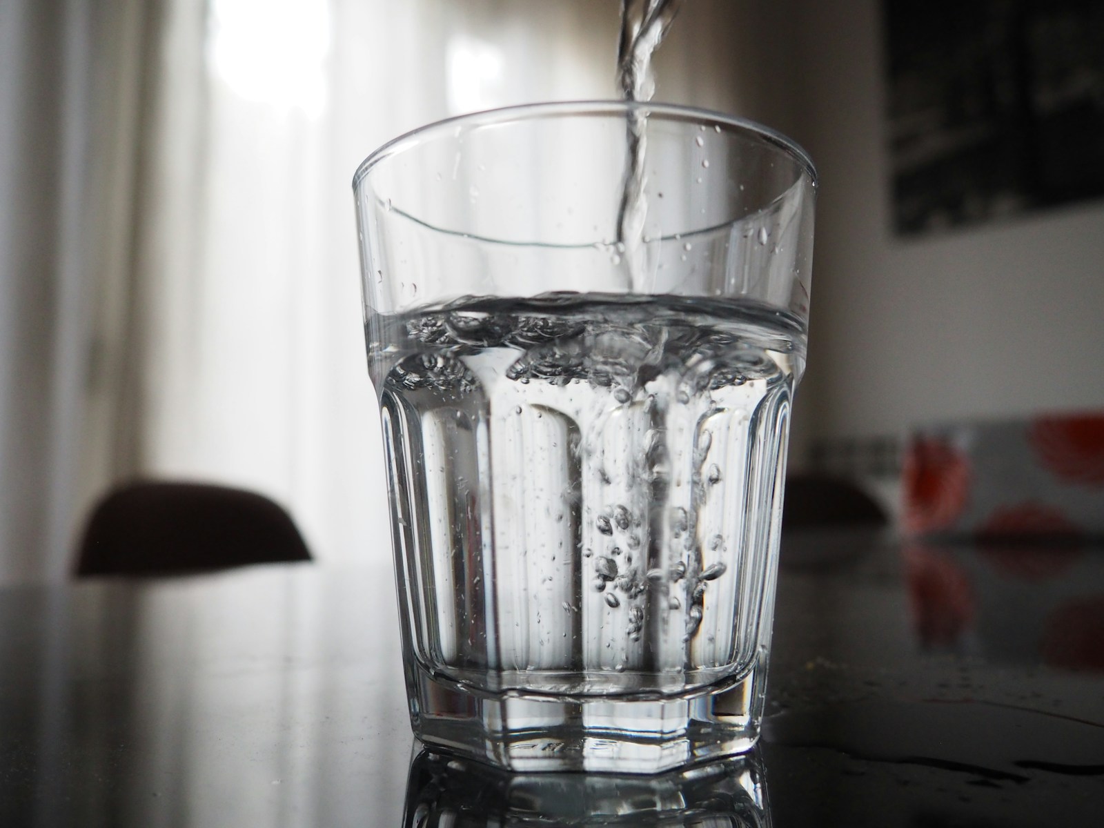 Water being poured into a clear glass, a reminder to keep fluids up alongside steady fiber and protein while on a GLP-1.