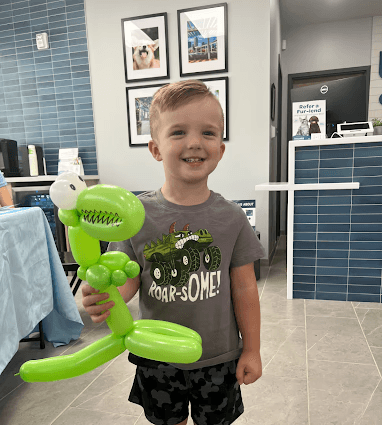 Little Boy holding Green Dinosaur Balloon Twist