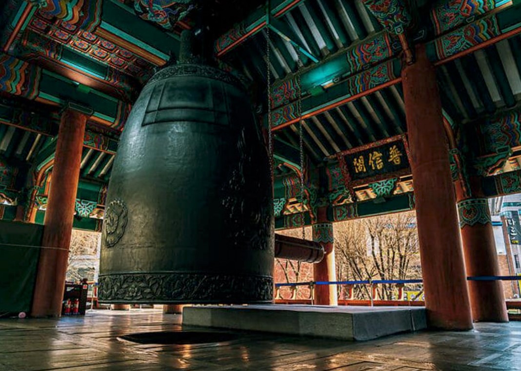 A blank white card resting on a softly draped rust-colored fabric atop a beige quilted surface.