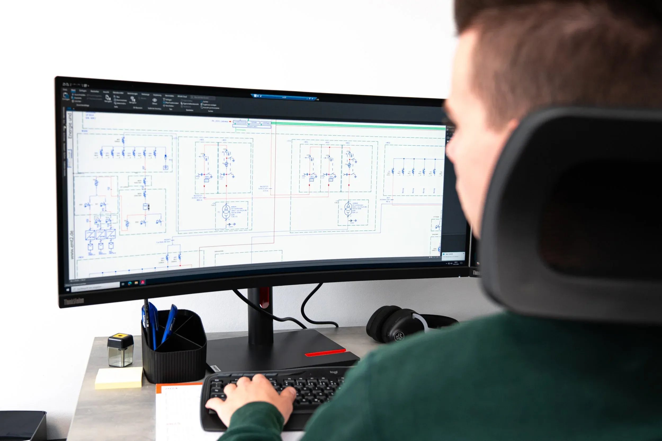 Mann programmiert Schaltplan am gebogenen Bildschirm.