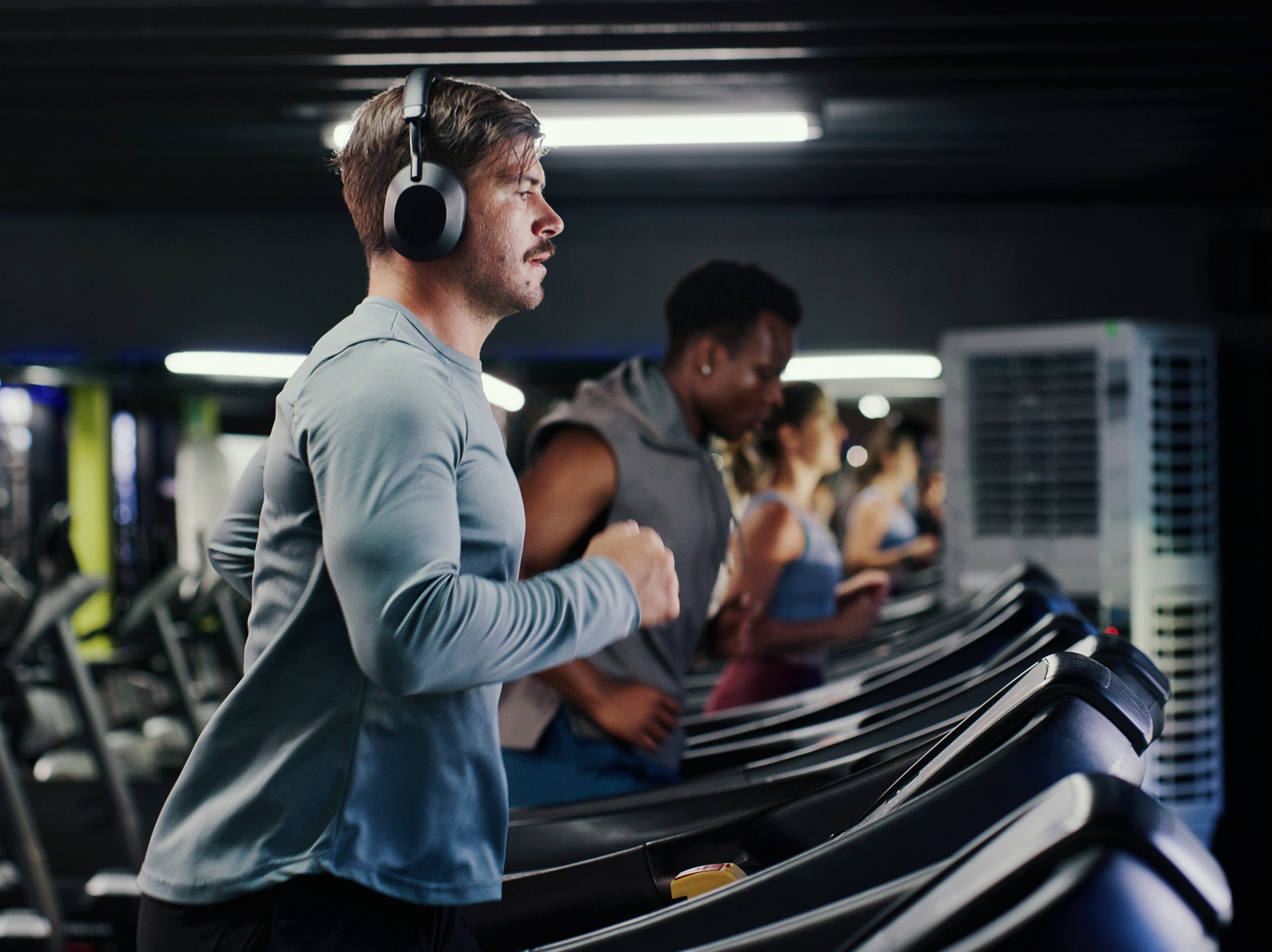 man with headphones on at the gym running to do a treadmill incline workout for weight loss