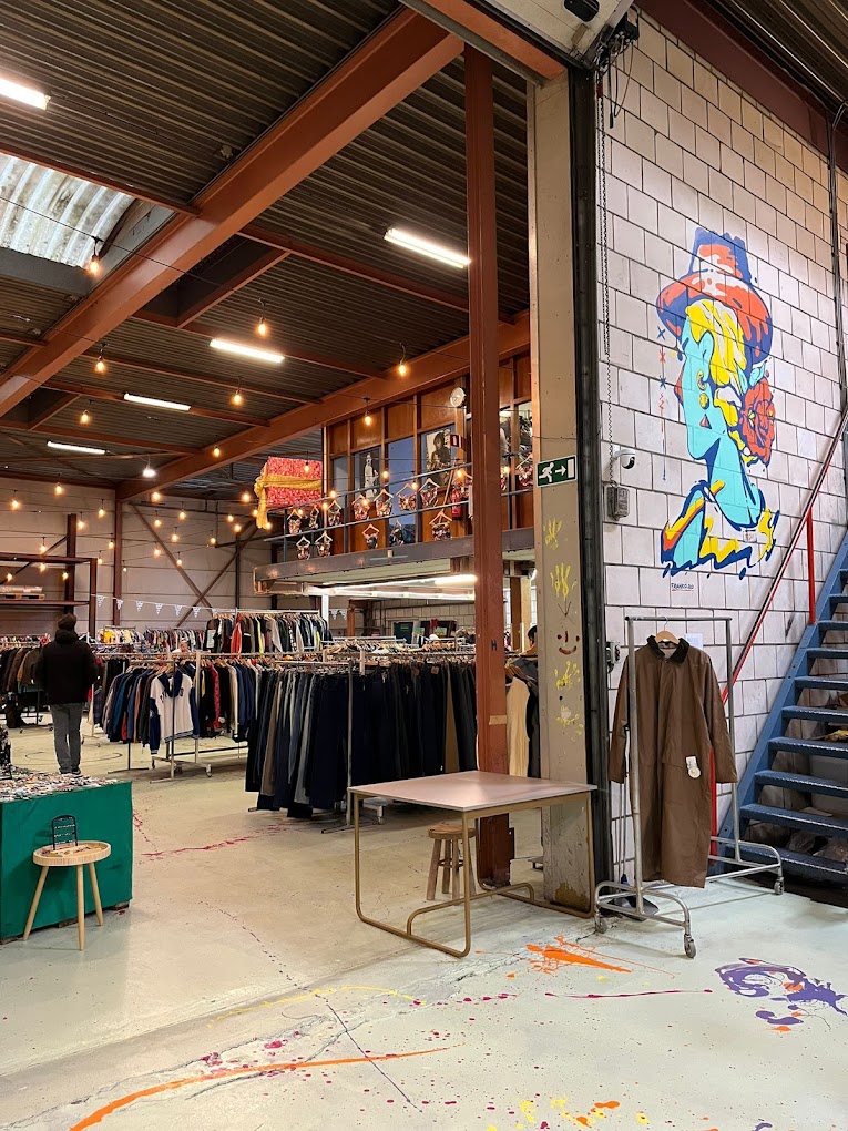 A spacious workshop with tools, equipment, and a colorful mural on the wall, featuring rustic wooden beams.
