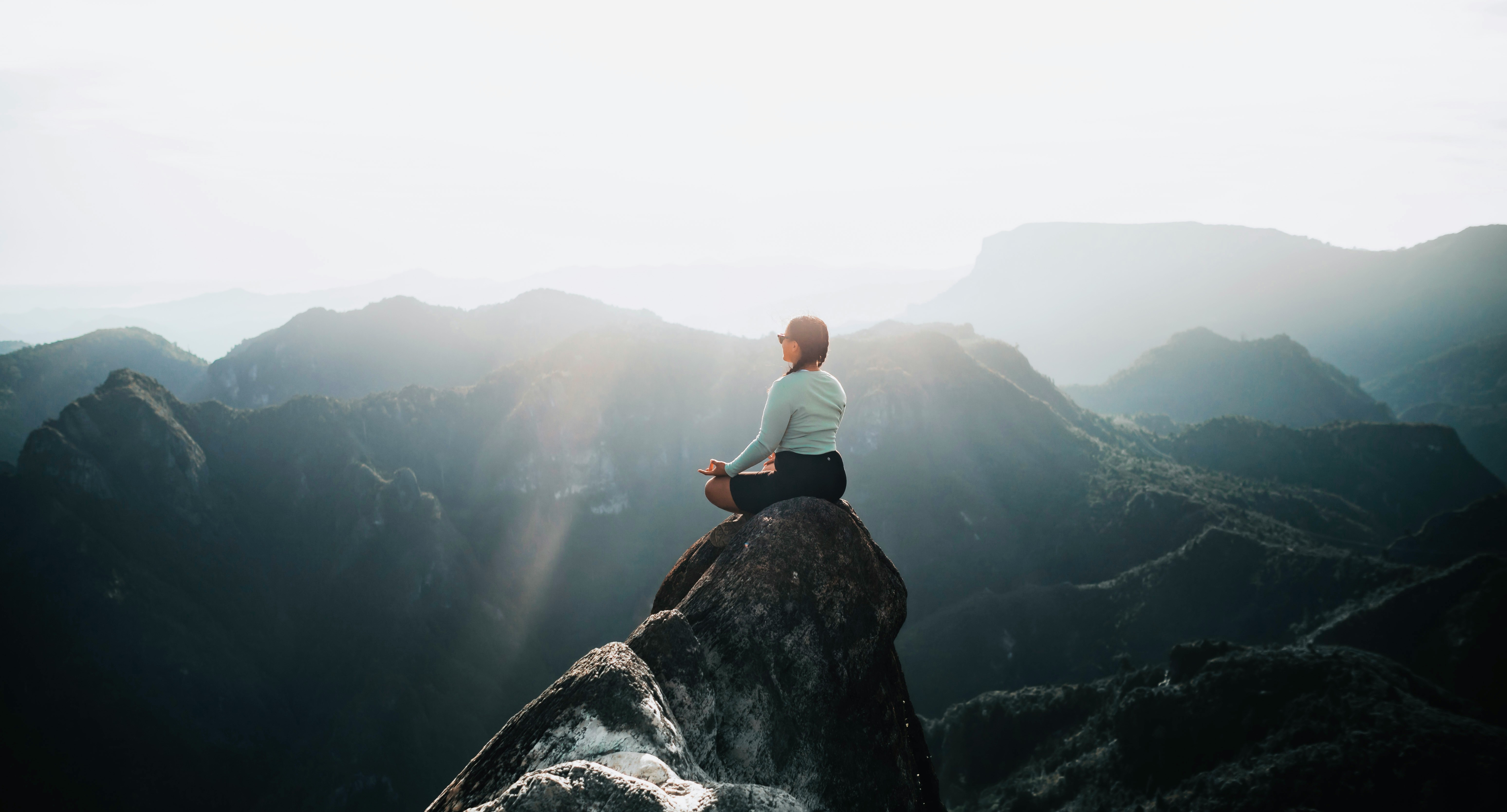 a man sitting on top of a large rock